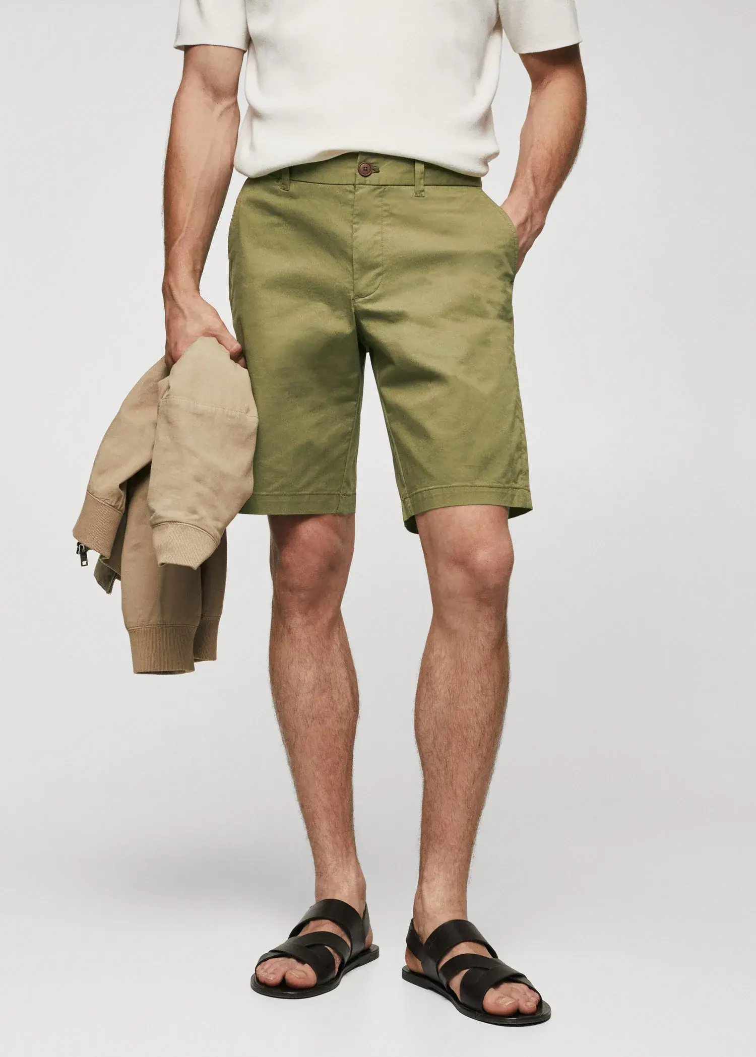 Mango Chino Bermuda shorts. a man in green shorts holding a tan jacket. 