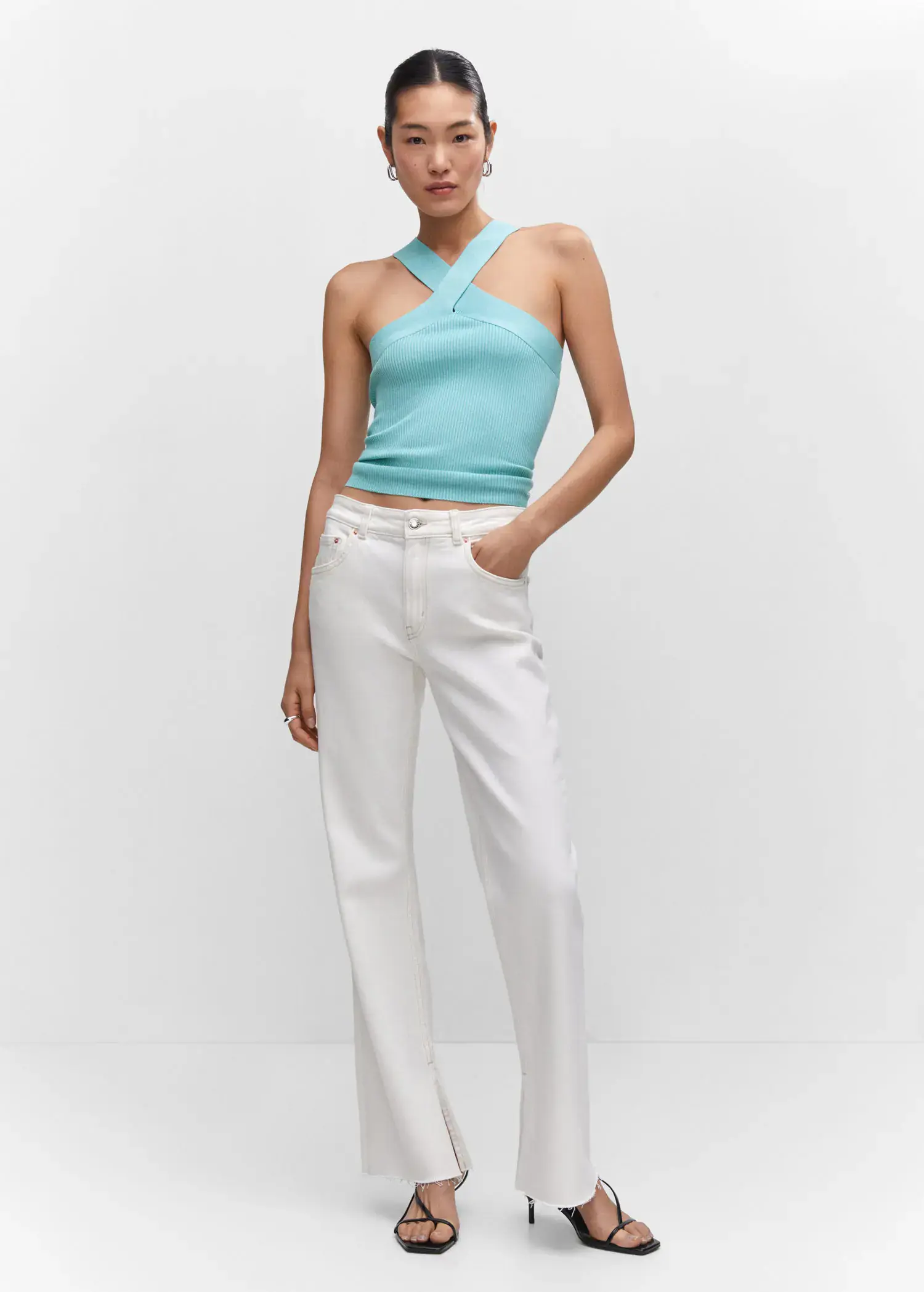 Mango Halter-neck knitted top. a woman wearing a blue top and white pants. 