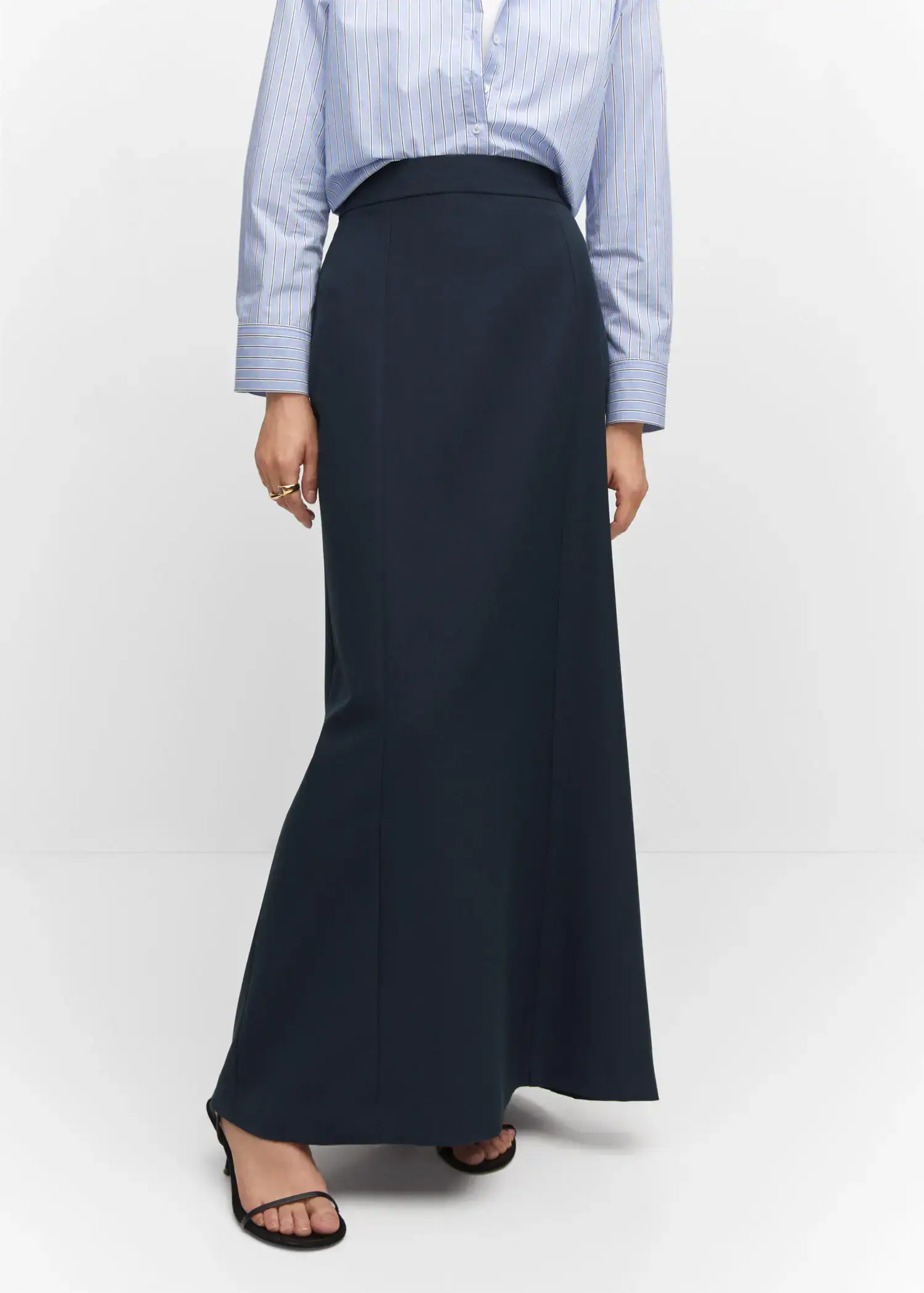 Mango Flowy long skirt. a woman wearing a long black skirt standing in front of a white wall. 