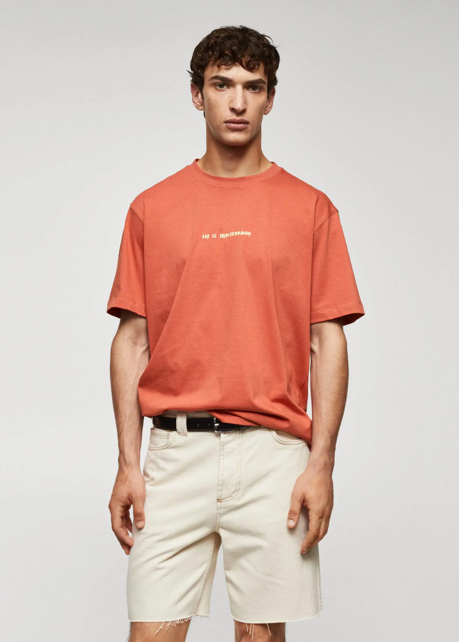 Mango Adriana Eskenazi x Mango t-shirt. a man wearing a red shirt and beige shorts. 
