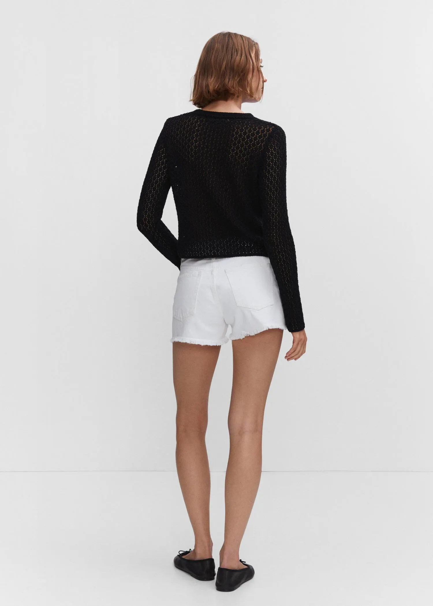 Mango Broken denim shorts. a woman wearing white shorts and a black sweater. 