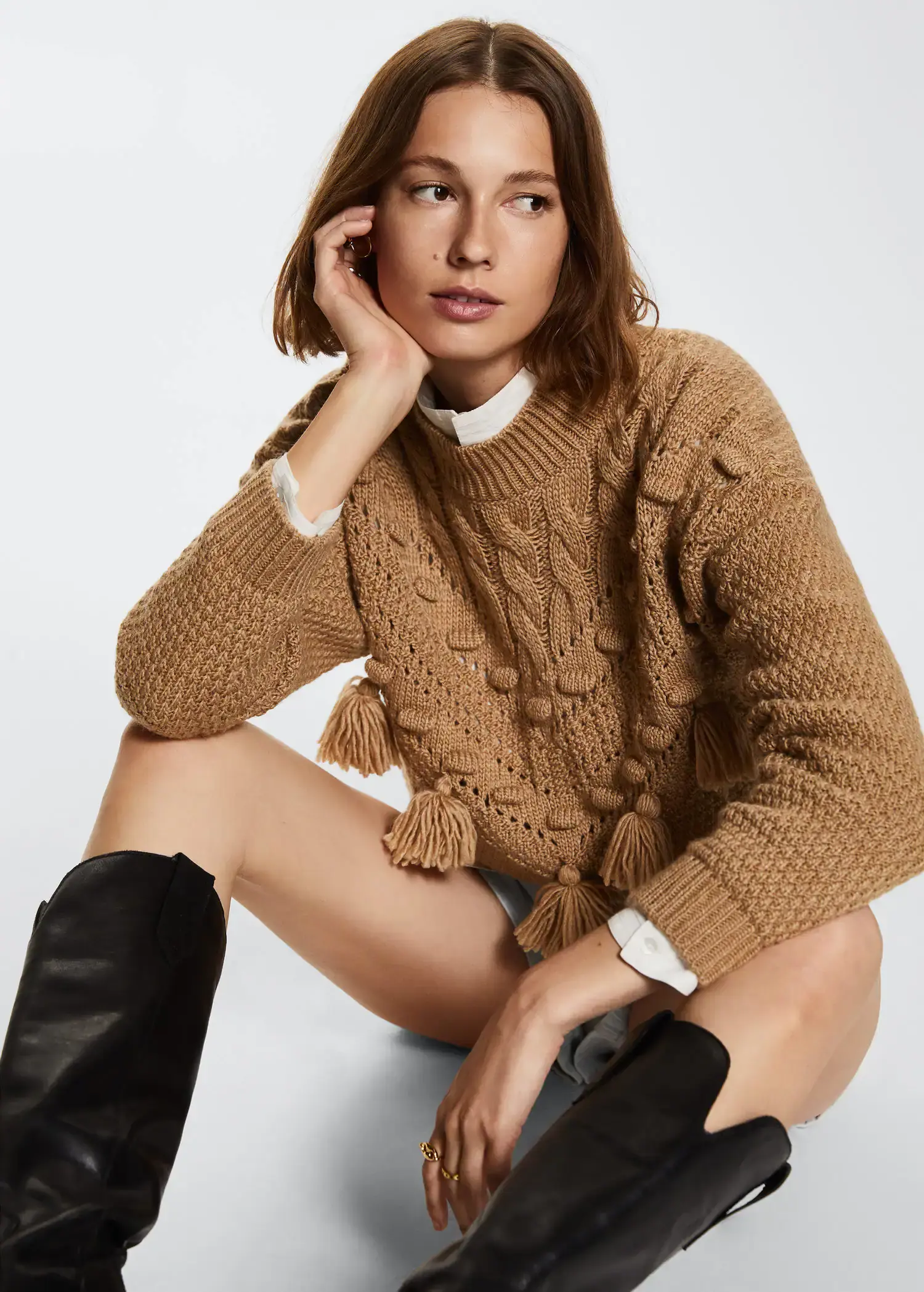 Mango Openwork pompoms knit sweater. a woman sitting on the ground wearing boots. 