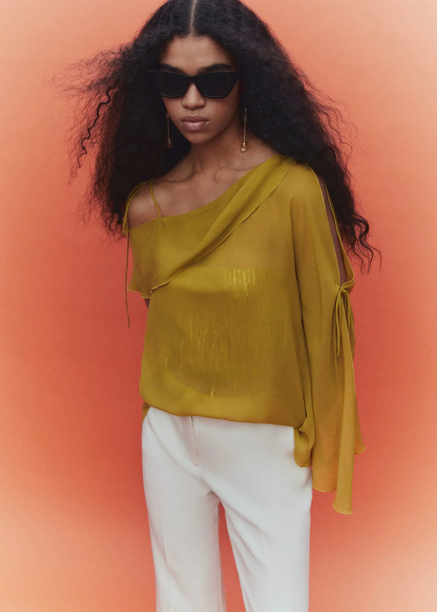 Mango Asymmetrical blouse with bows. a woman wearing a yellow top and white pants. 