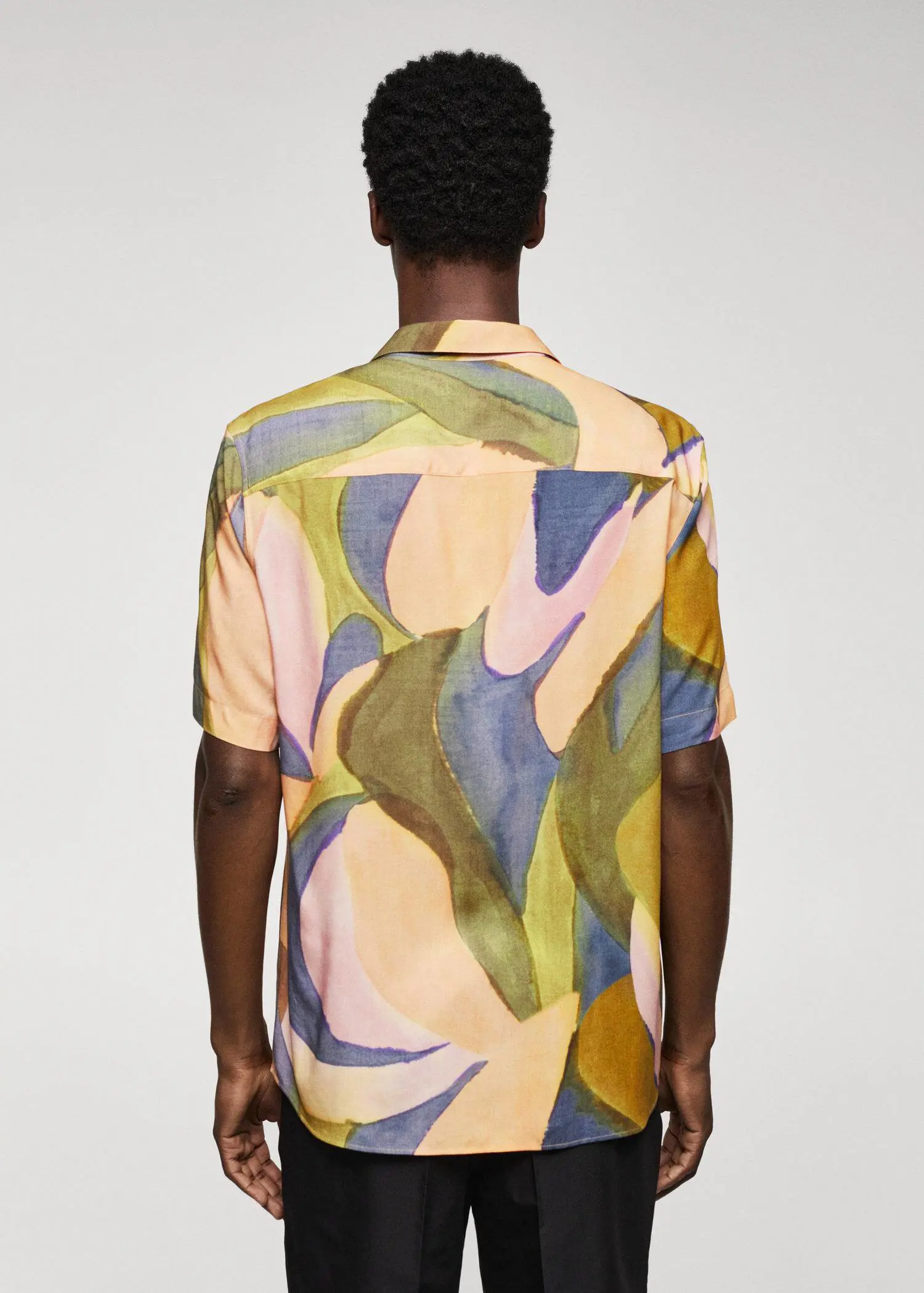 Mango Printed short-sleeved shirt. a person wearing a colorful shirt standing in front of a wall. 