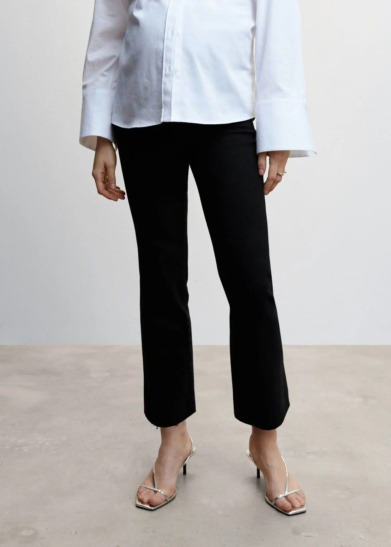 Mango Maternity flared cropped jeans. a woman wearing black pants and a white shirt. 
