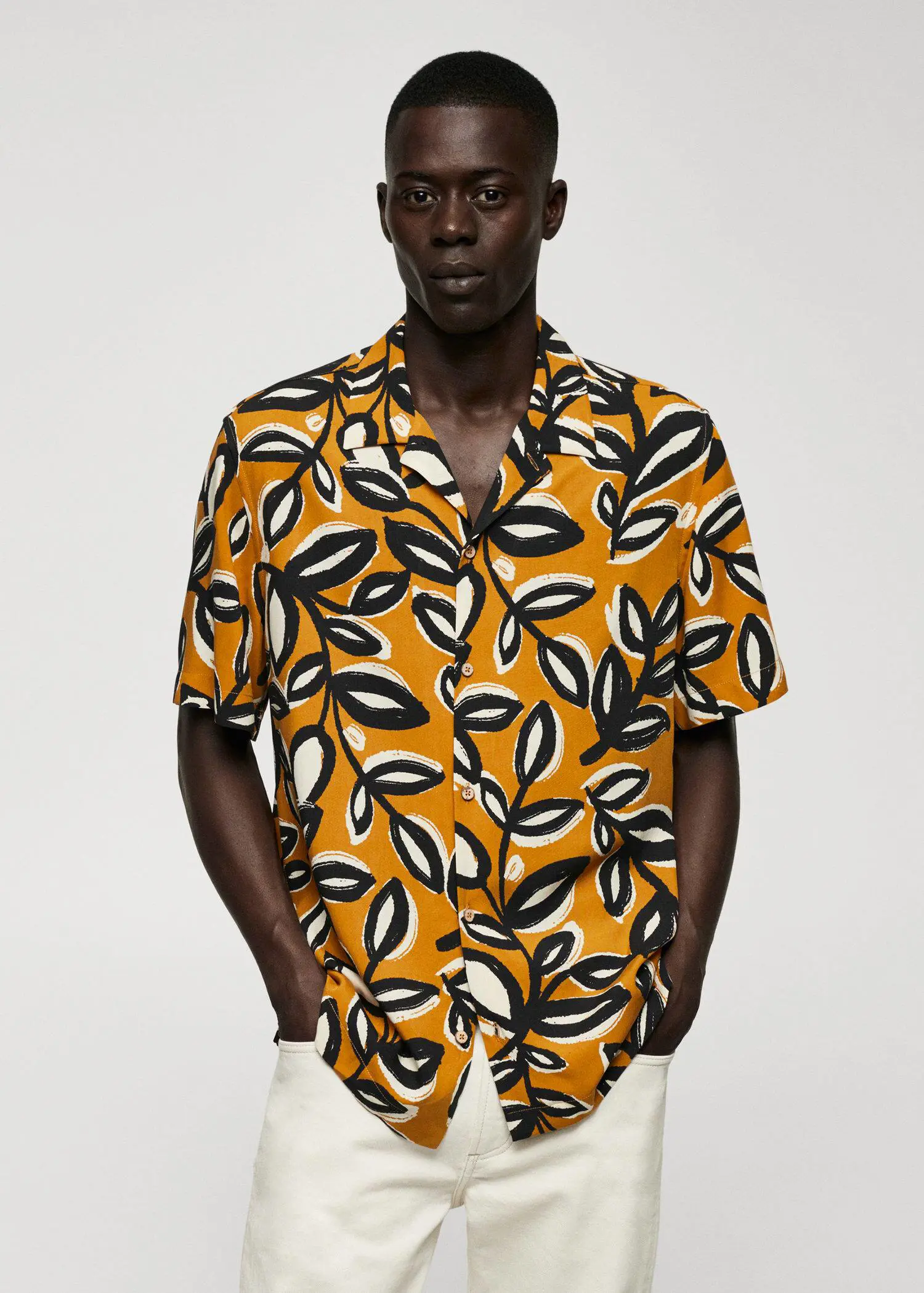 Mango Flowing leaf-print shirt. a man wearing a yellow and black leaf patterned shirt. 