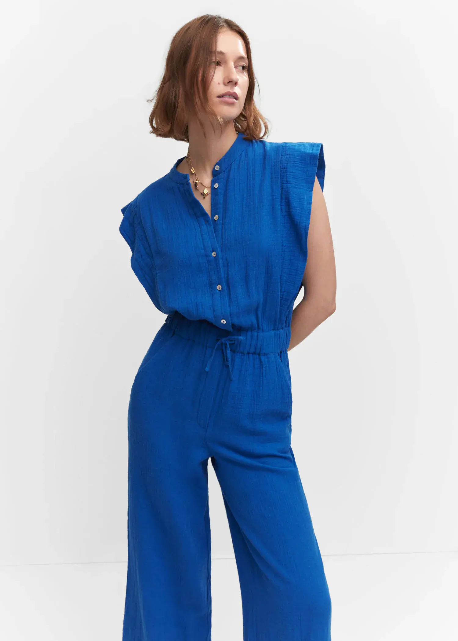 Mango Textured jumpsuit with button. a woman wearing a blue jumpsuit with a belt around the waist. 