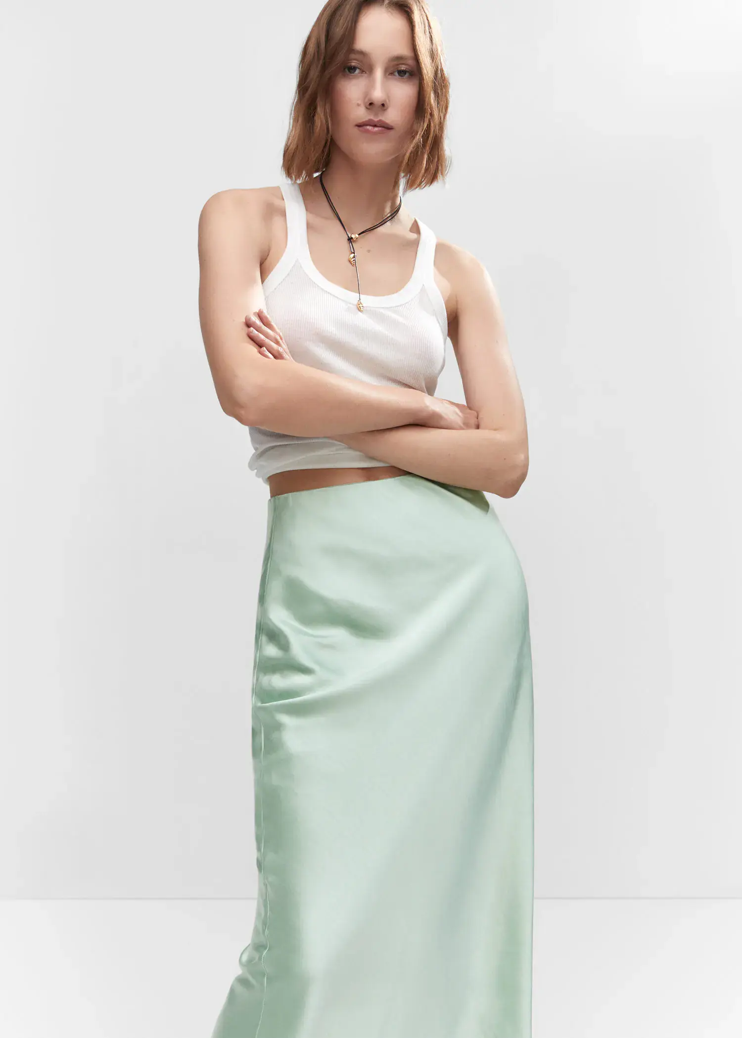 Mango Midi satin skirt. a woman wearing a white top and a green skirt. 