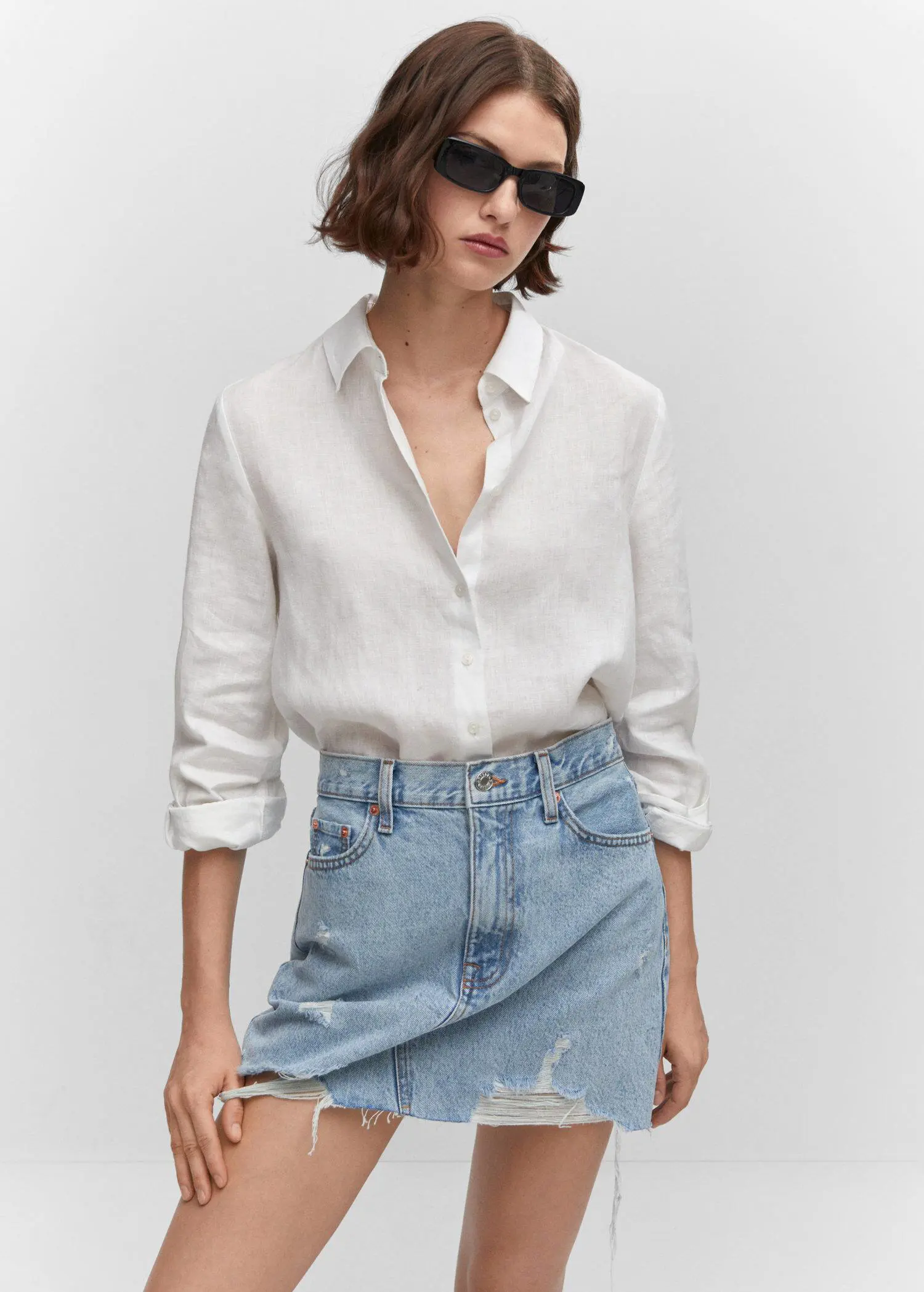 Mango Denim mini-skirt. a woman wearing a white shirt and a jean skirt. 
