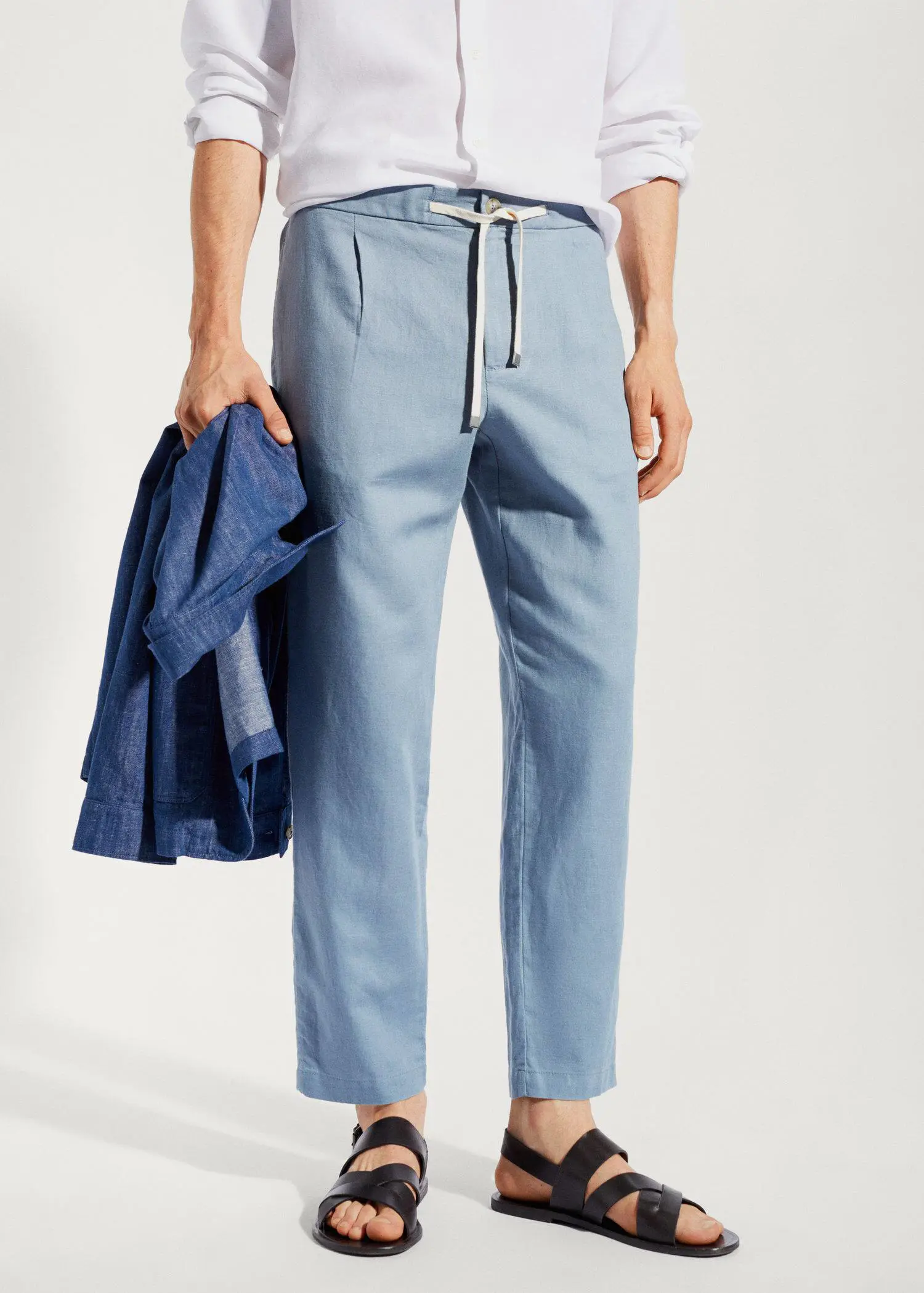 Mango Slim-fit pants with drawstring . a person holding a jacket and wearing blue pants. 