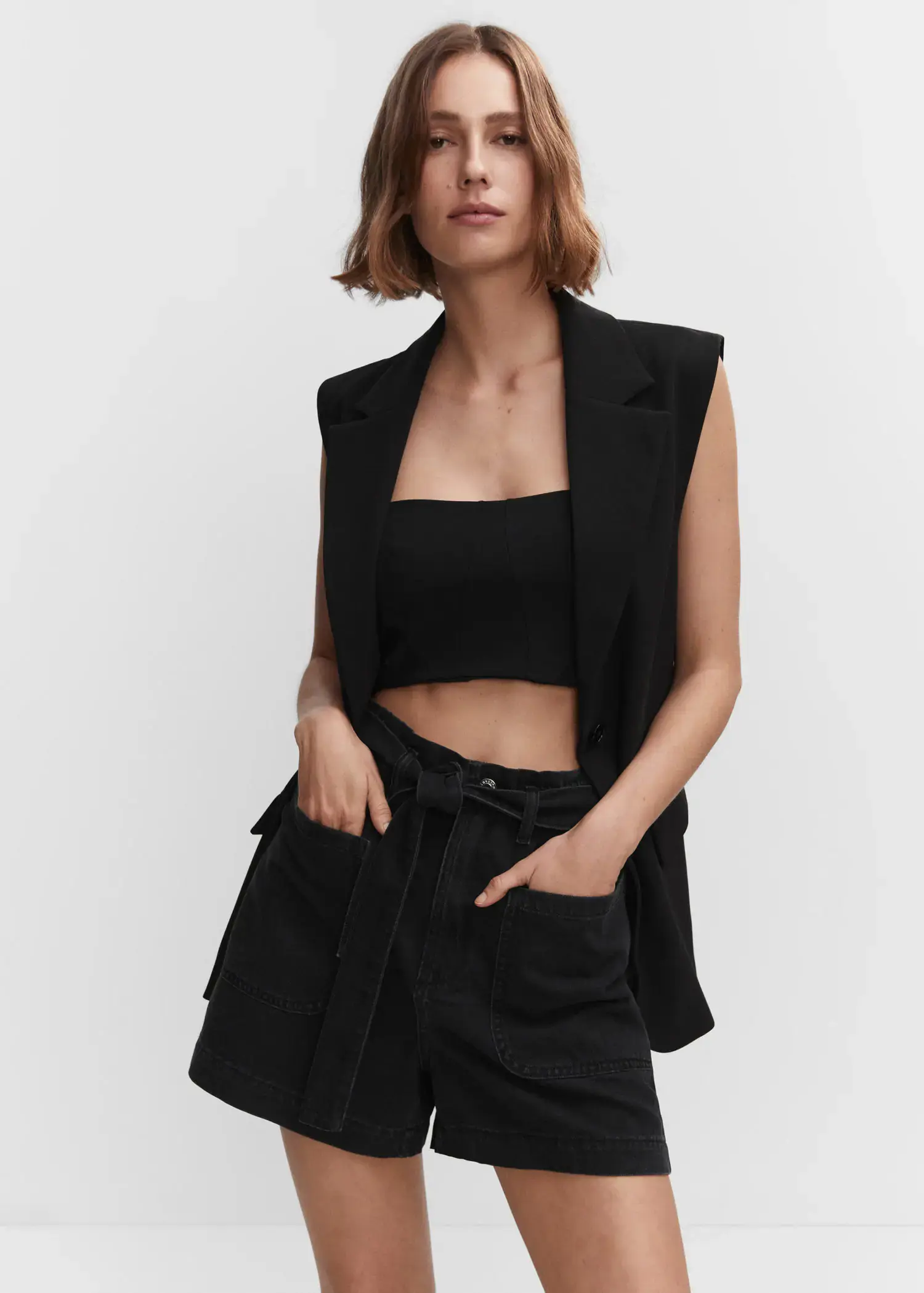 Mango Paperbag shorts with belt. a woman in a black outfit is posing. 