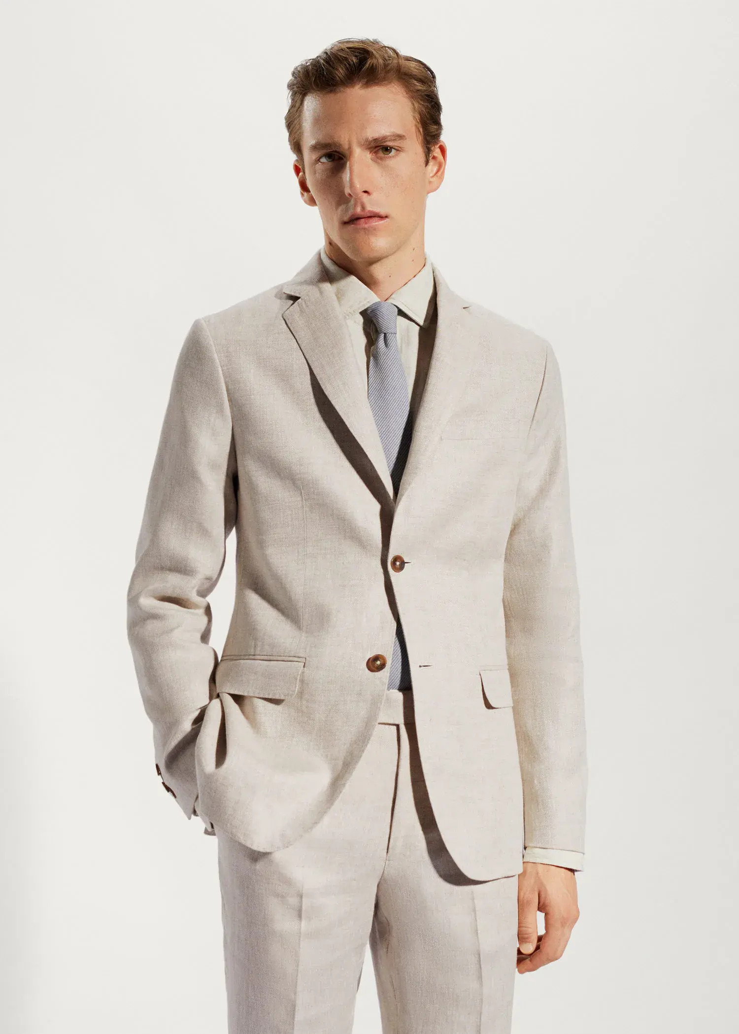 Mango 100% linen suit blazer. a man wearing a suit and tie standing in front of a wall. 