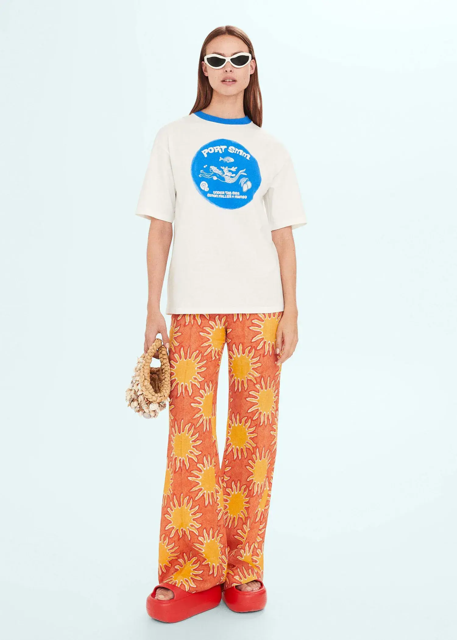Mango Printed oversize t-shirt. a person standing in front of a wall holding a bag. 