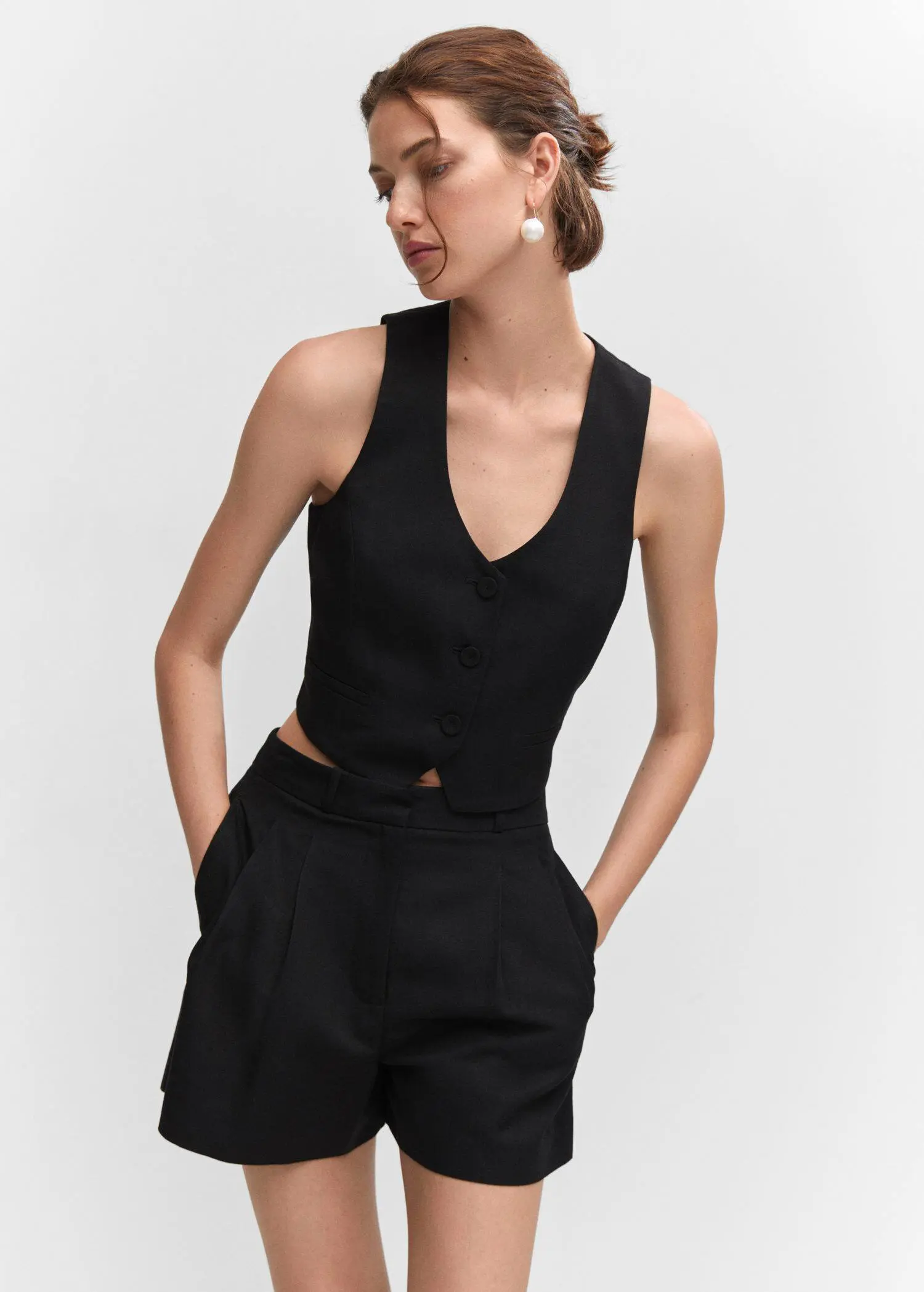 Mango Pleated high-waist shorts. a woman wearing a black top and black shorts. 