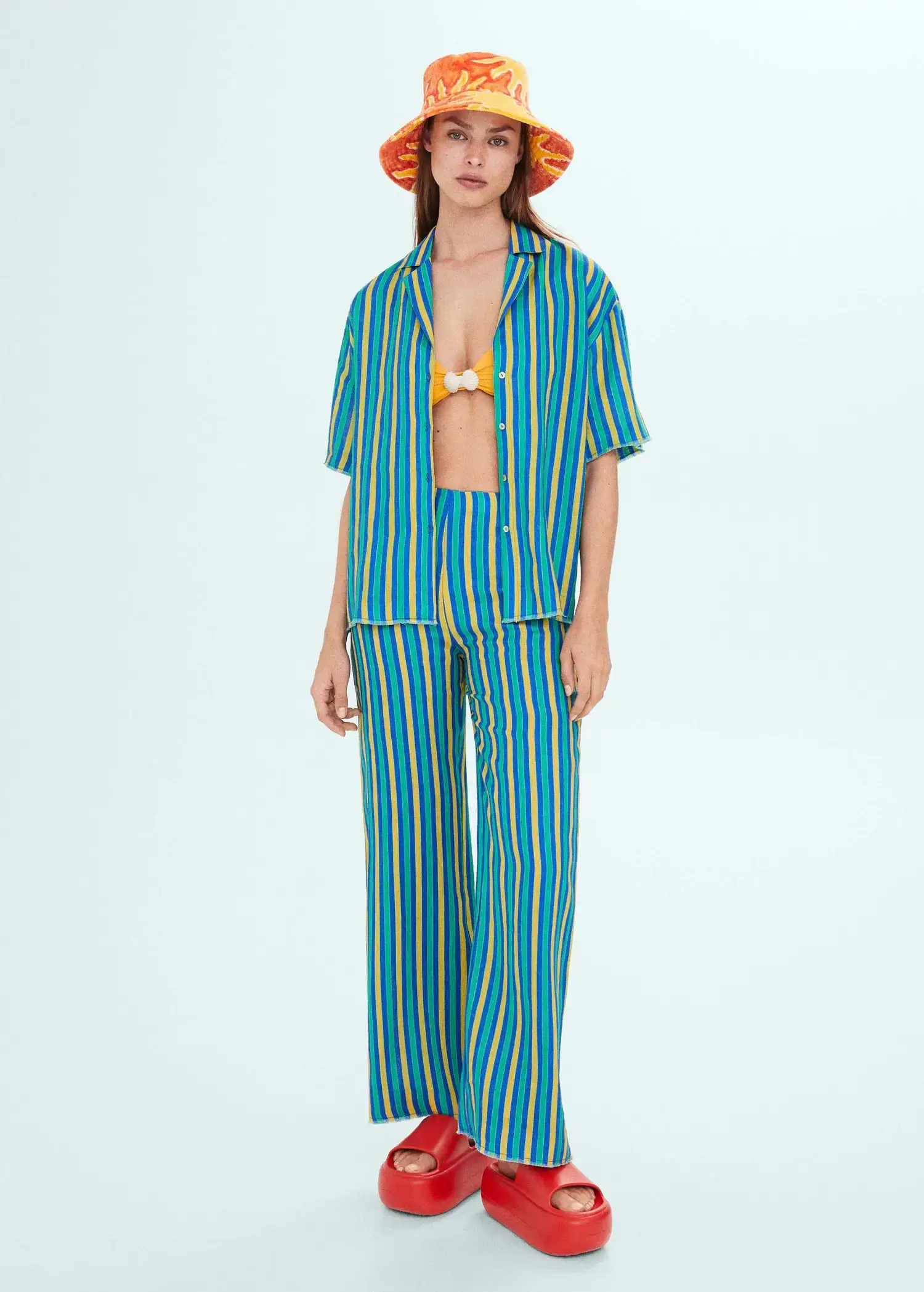 Mango Multi-coloured striped linen trousers. a woman in a blue and yellow striped outfit. 