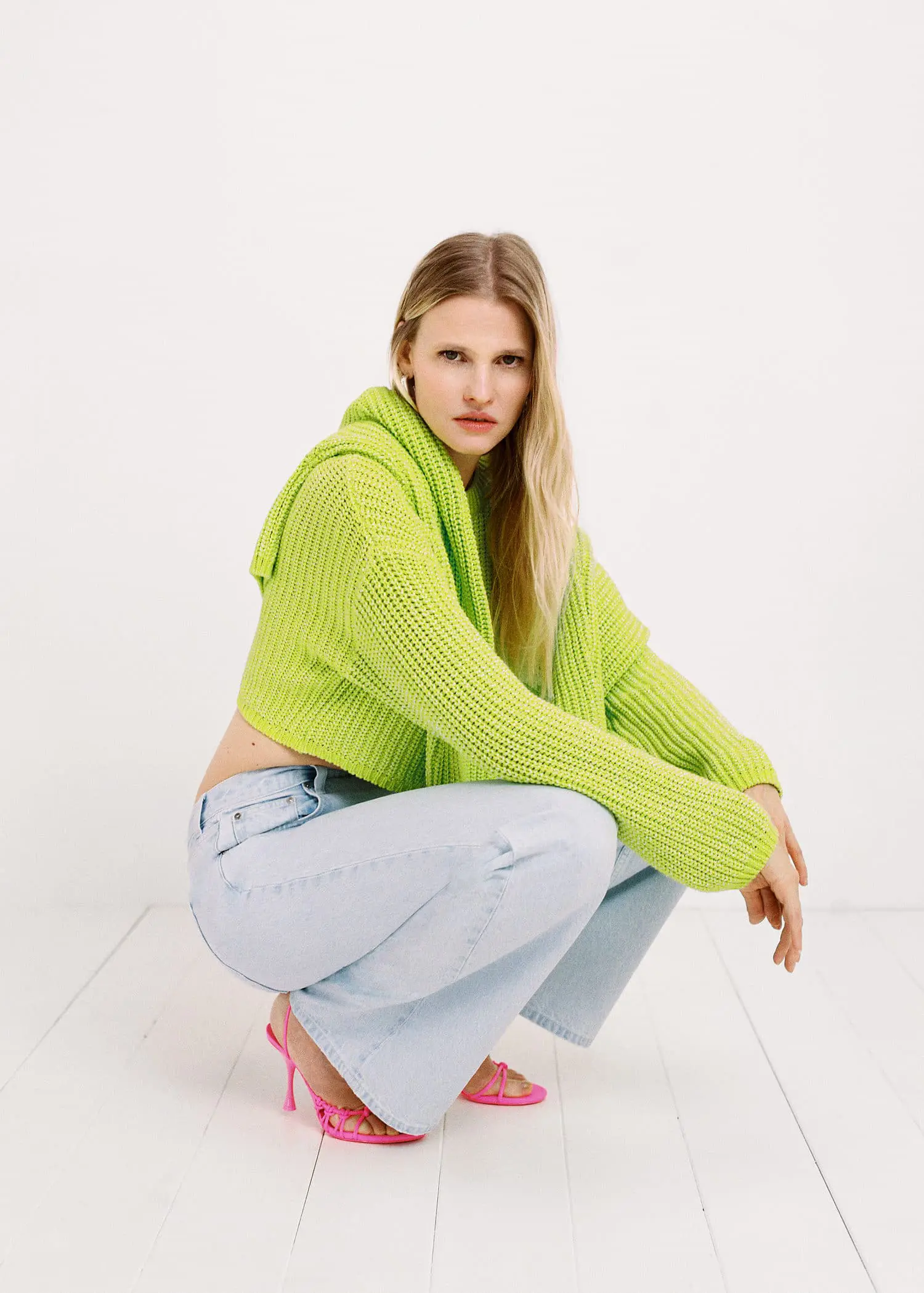 Mango Knitted cropped sweater. a woman squatting down wearing a bright green sweater. 
