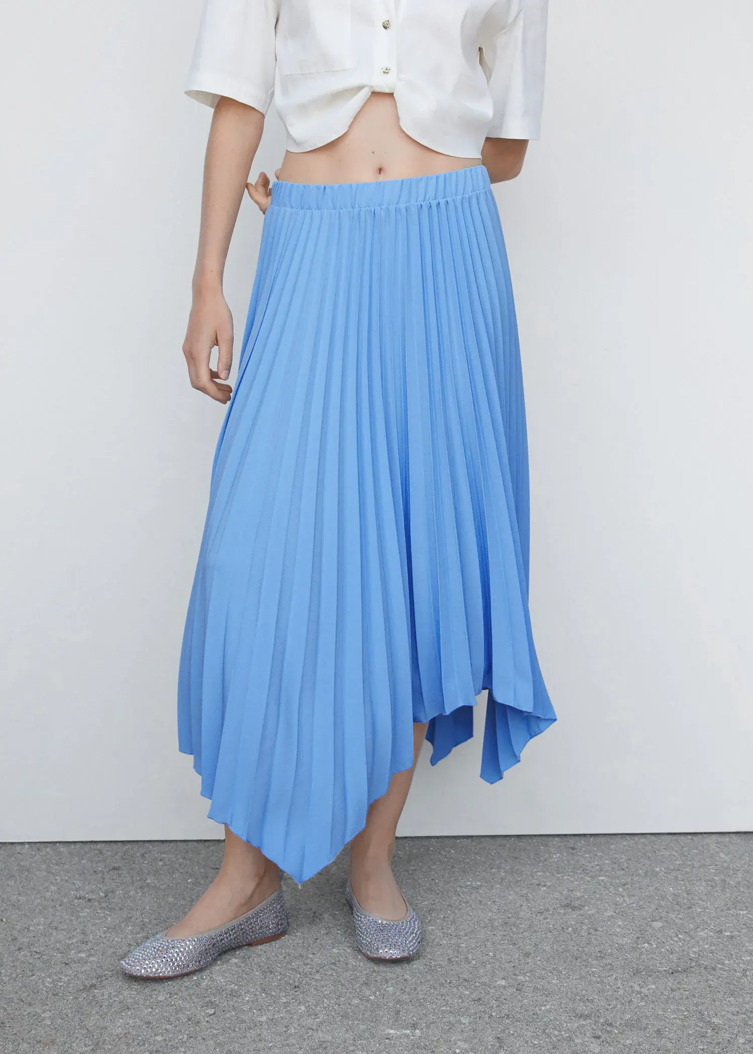Mango Pleated asymmetric skirt . a woman wearing a blue skirt standing in front of a white wall. 