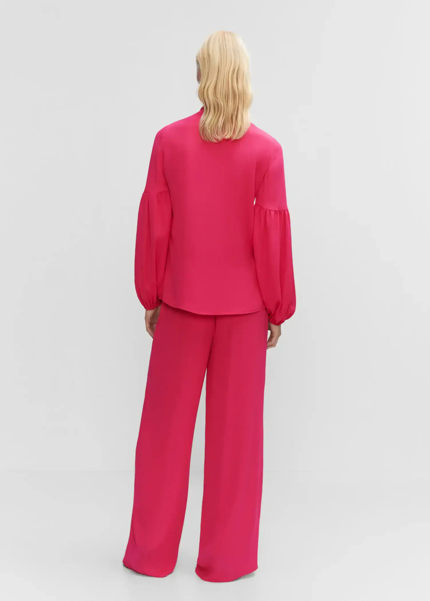Mango Blouse with puffed sleeves and bow . a person wearing a pink outfit standing in a room. 