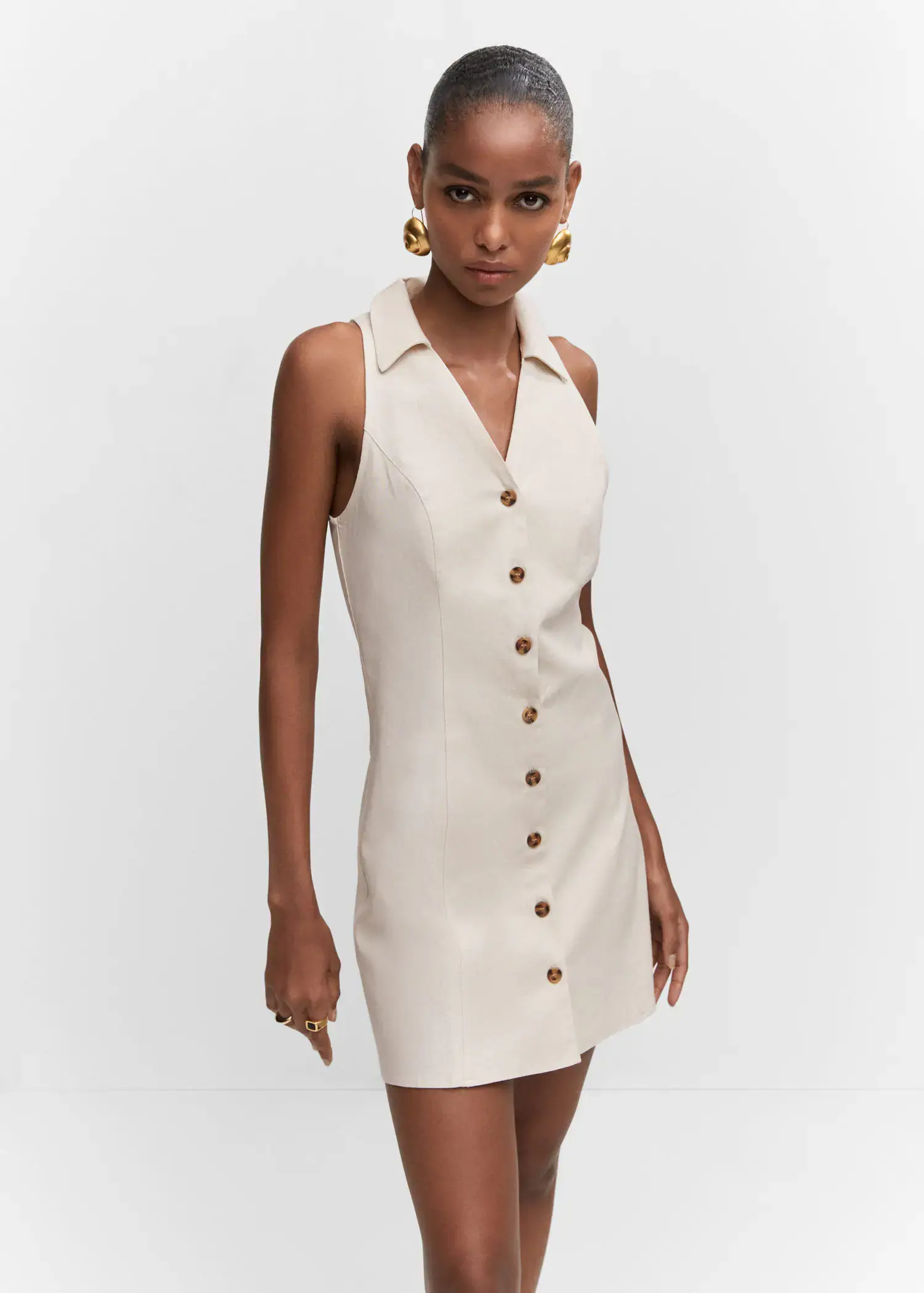 Mango Ramie dress with buttons. a woman wearing a white dress and gold earrings. 