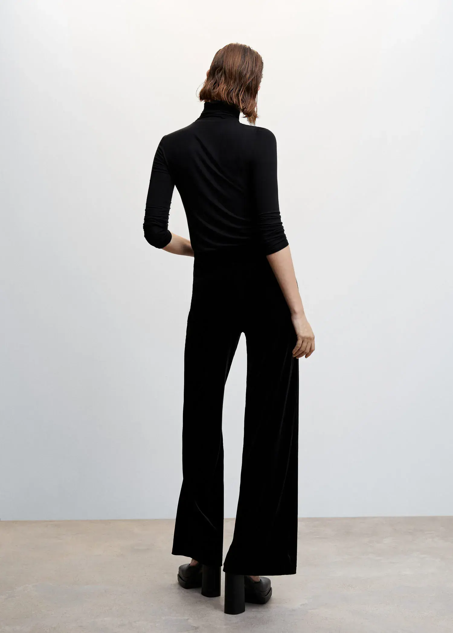 Mango Velvet palazzo pants. a woman wearing a black outfit standing in a room. 