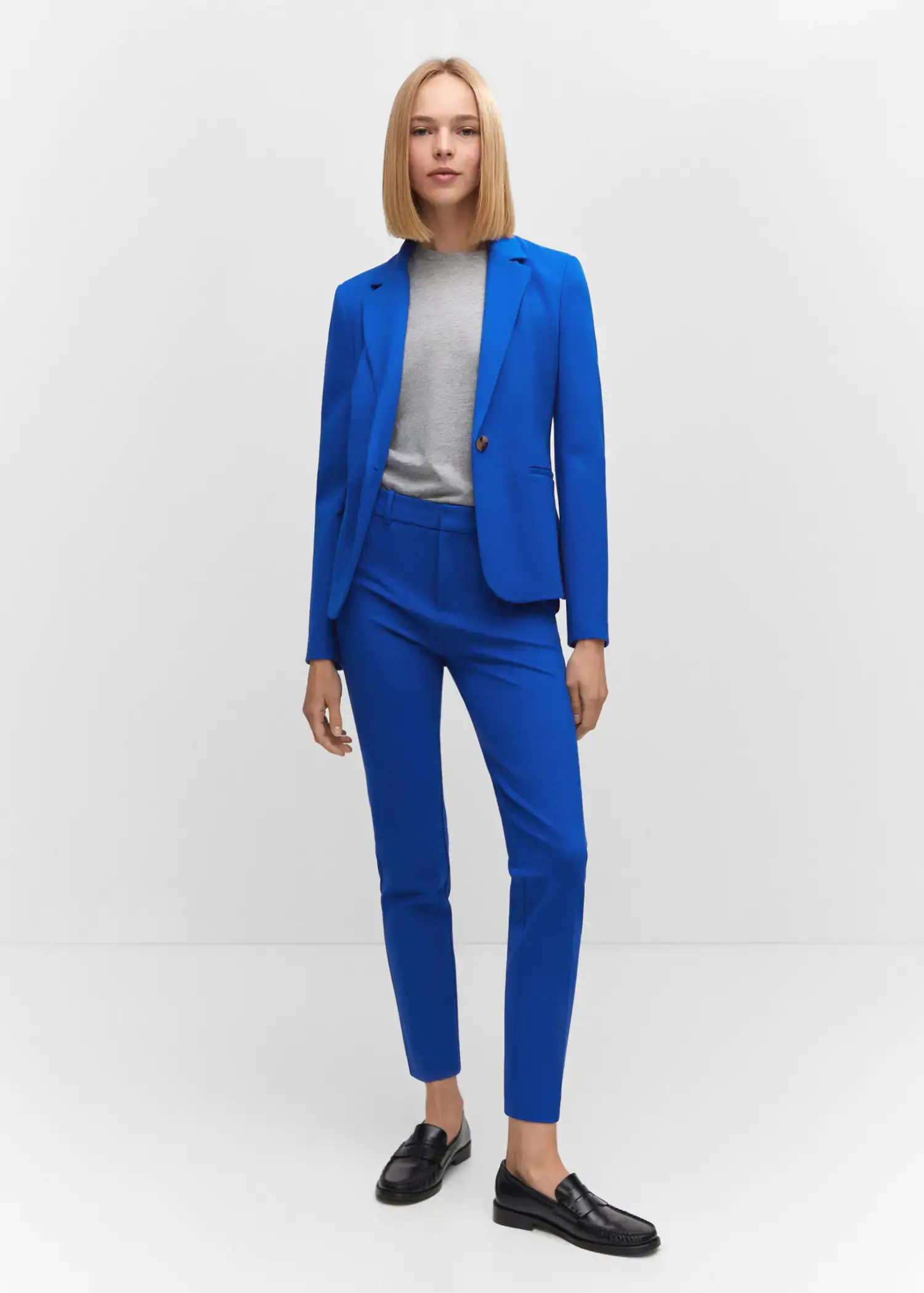 Mango Fitted blazer with blunt stitching. a woman wearing a blue suit standing in a room. 