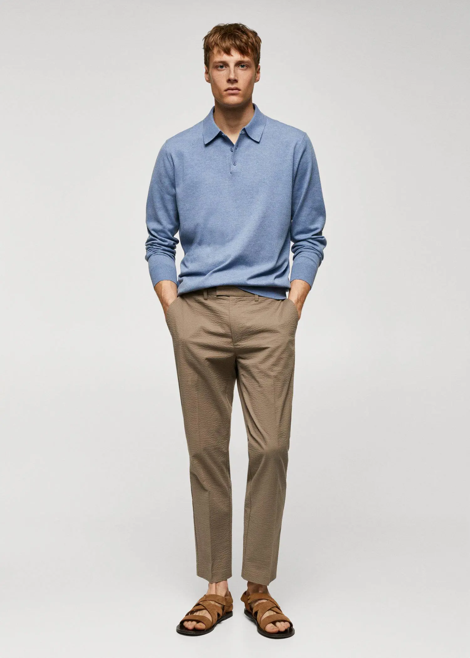 Mango Long-sleeved cotton jersey polo shirt. a man standing in front of a white wall. he is holding his hands in his pockets. 