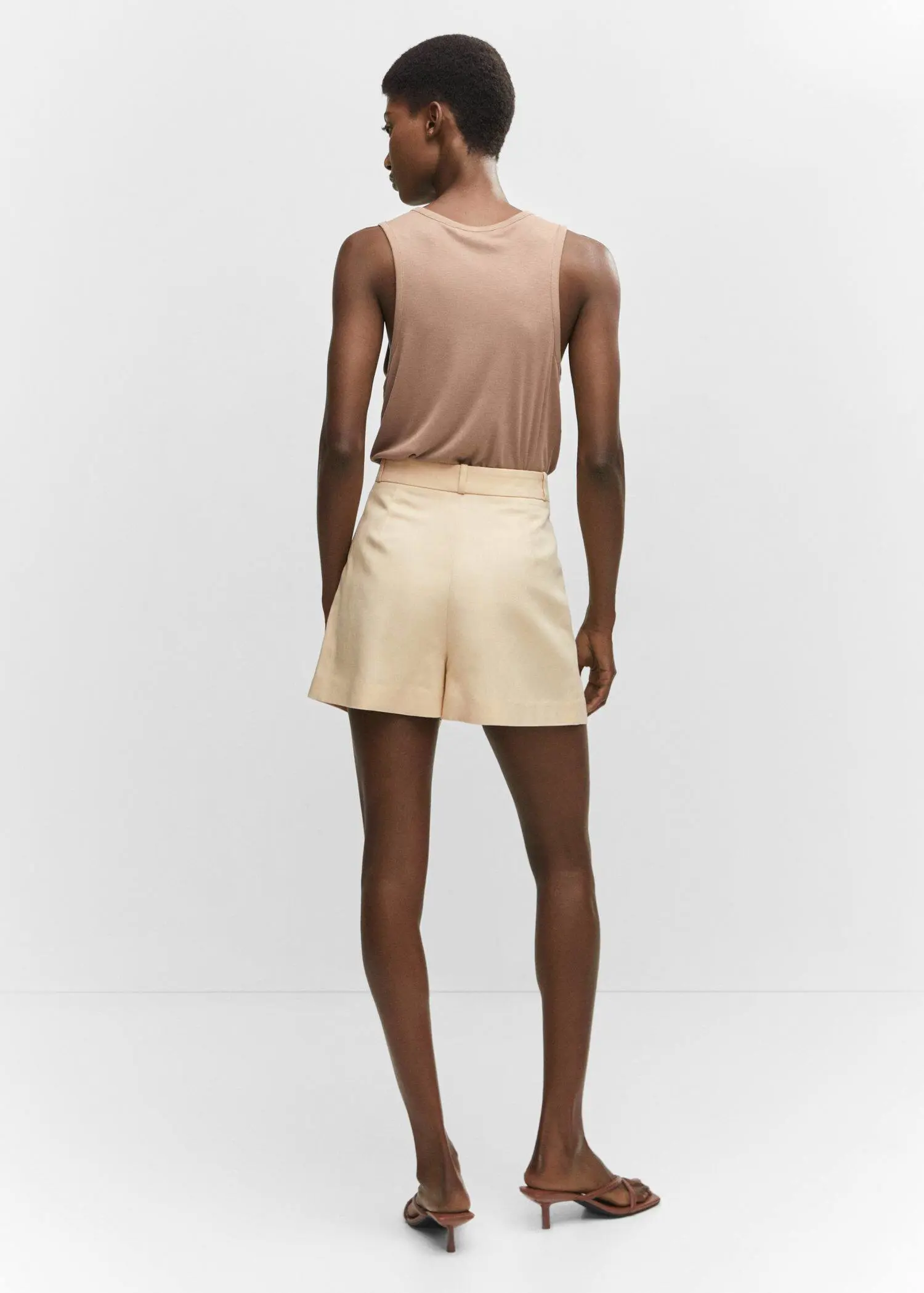 Mango Pleated mid-rise shorts. a man wearing a tan tank top and shorts. 