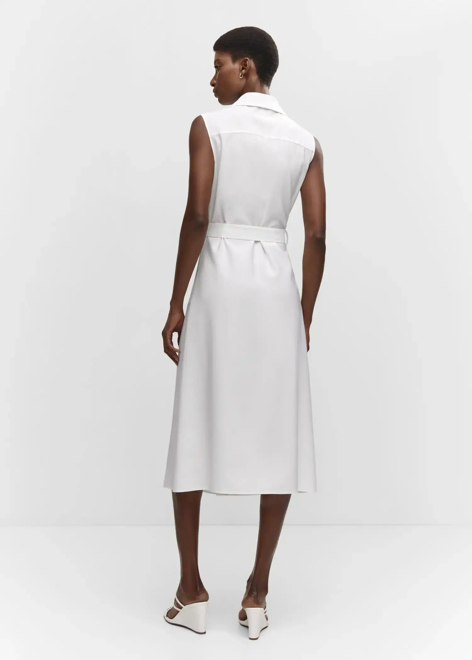 Mango Buttoned wrap dress. a woman wearing a white dress standing in front of a wall. 