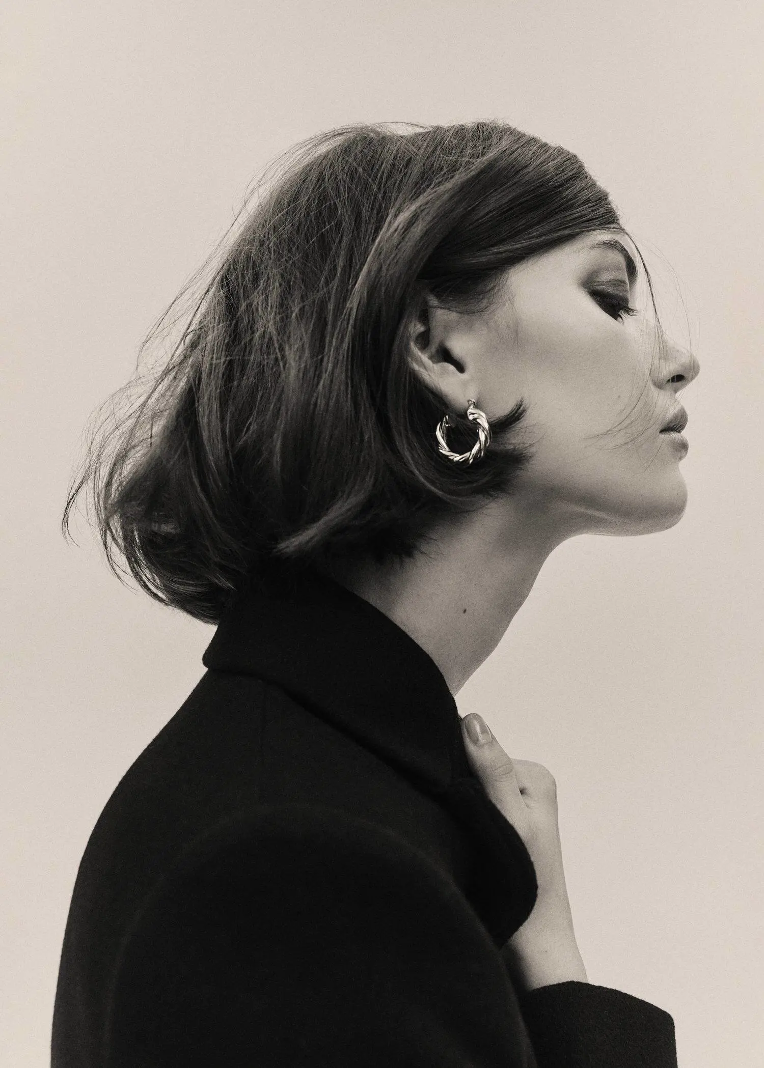 Mango Intertwined hoop earrings. a black and white photo of a woman wearing a black jacket. 