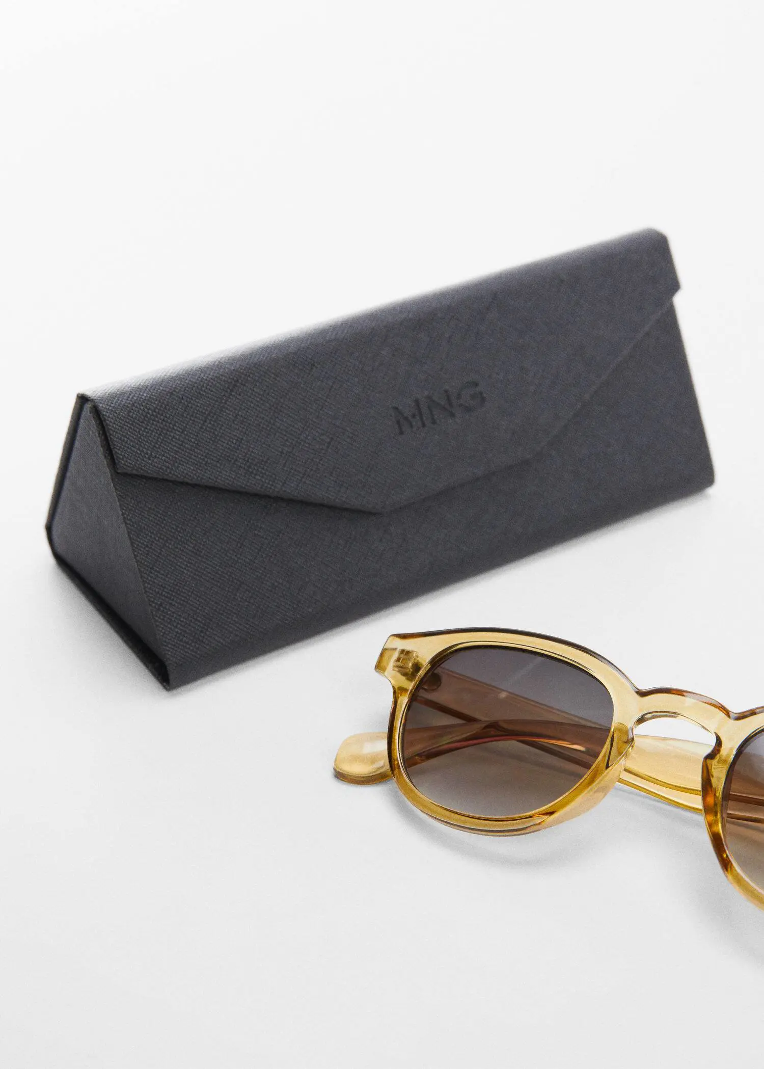 Mango Rounded sunglasses. a pair of sunglasses sitting on top of a table next to a case. 