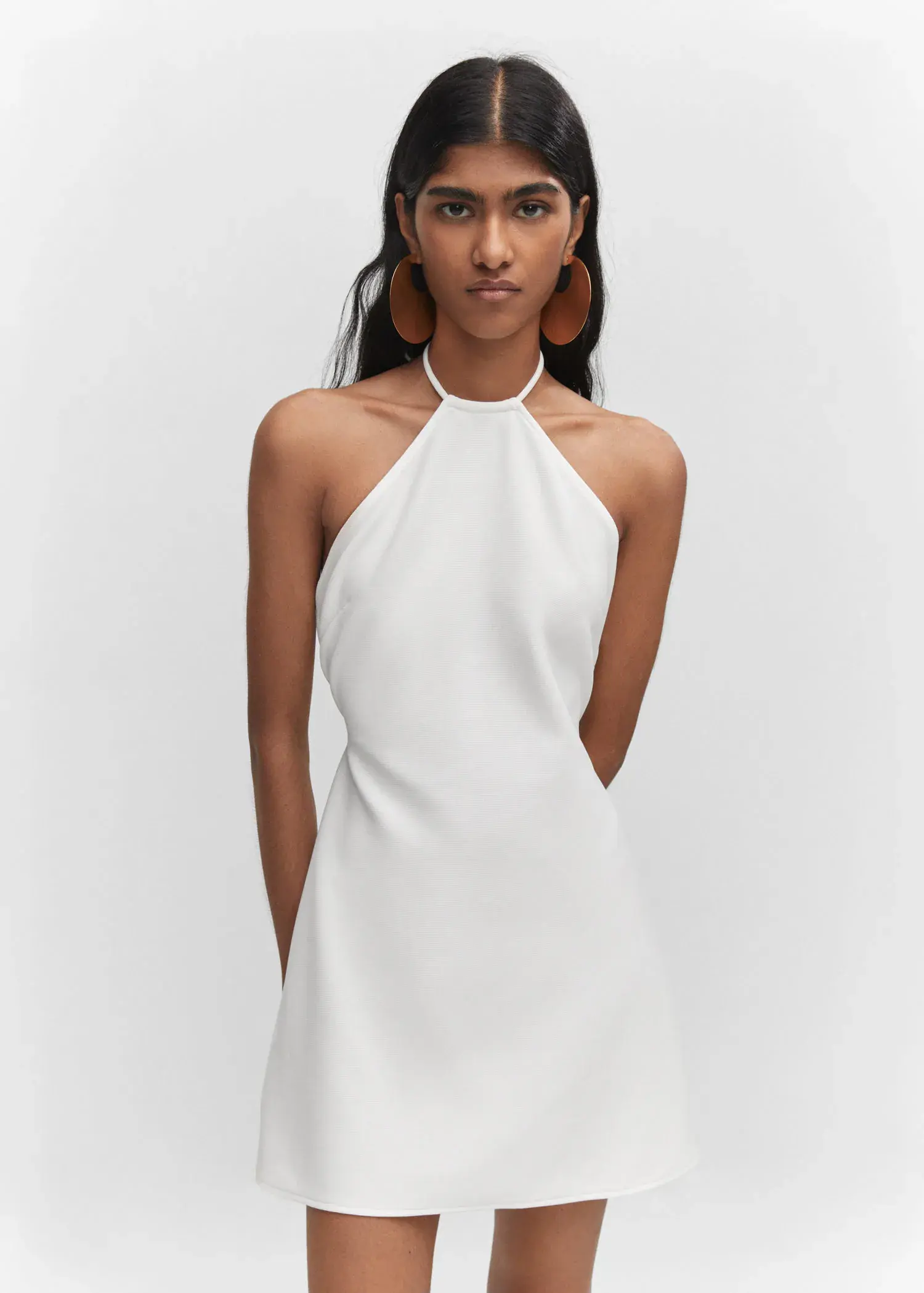 Mango Halter-neck dress with metal detail. a woman wearing a white dress and earrings. 