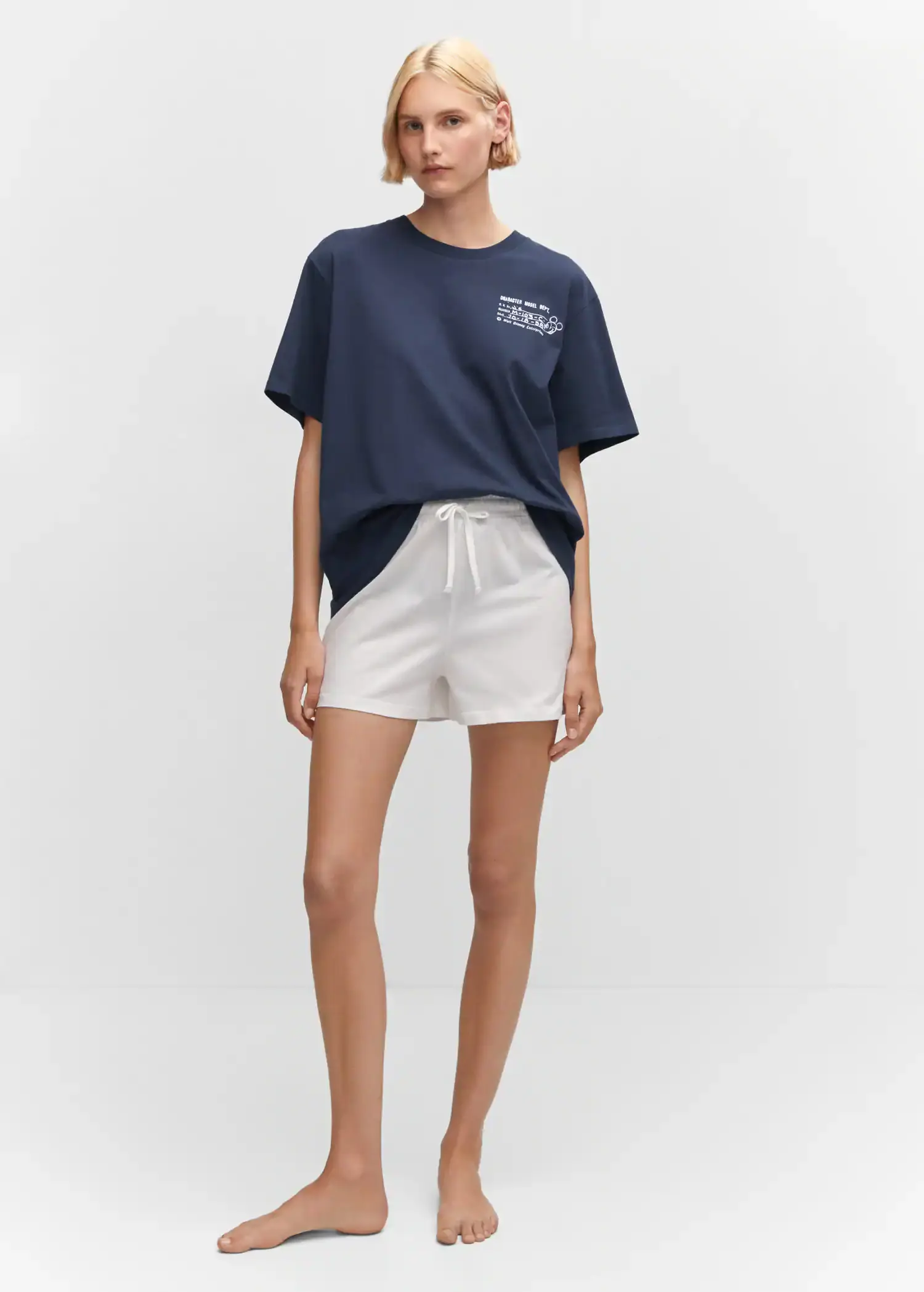 Mango Mickey Mouse cotton t-shirt. a woman wearing white shorts standing in front of a white wall. 