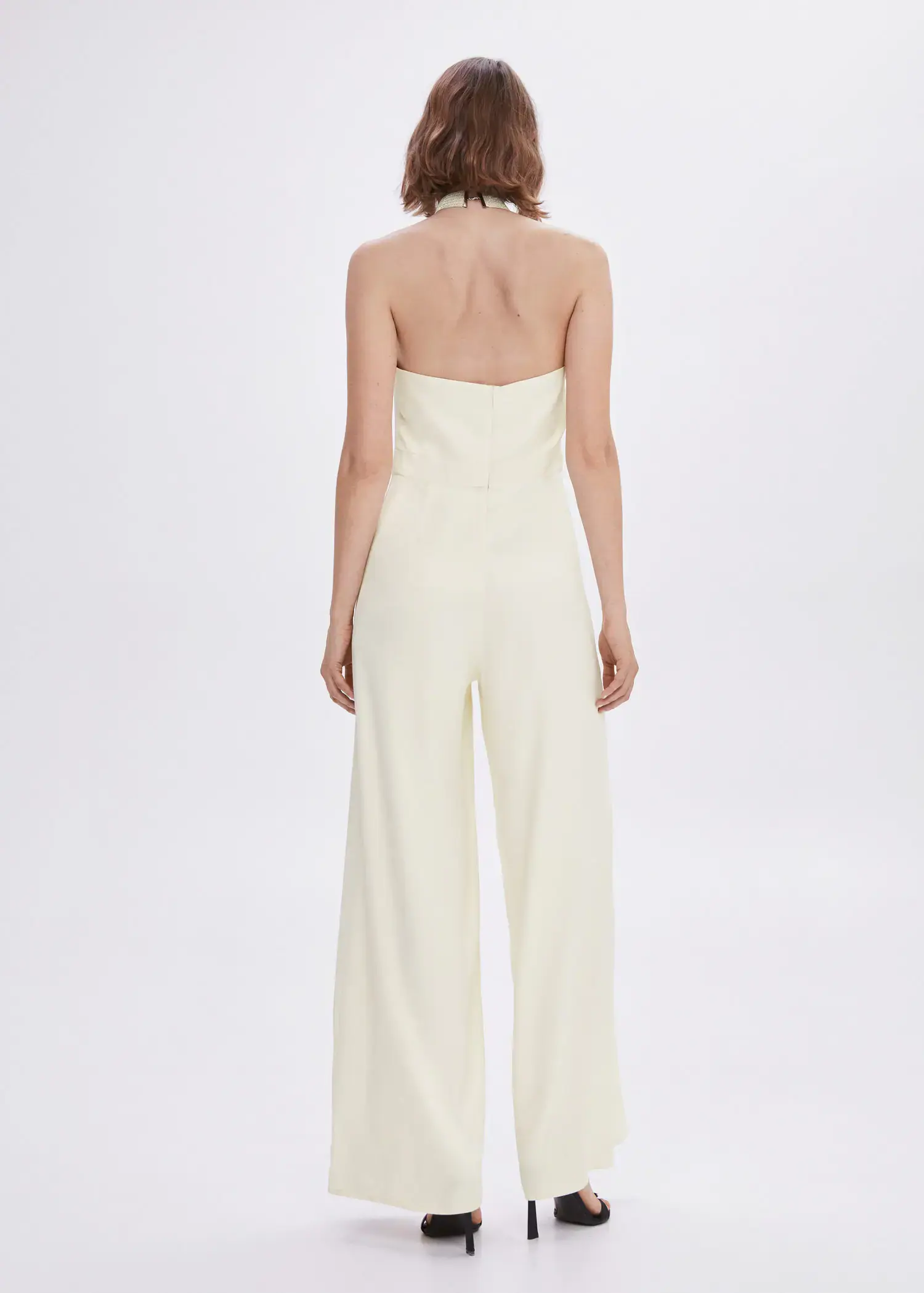 Mango Halter-neck jumpsuit with metallic detail. a woman in a white jumpsuit is standing in front of a white wall. 