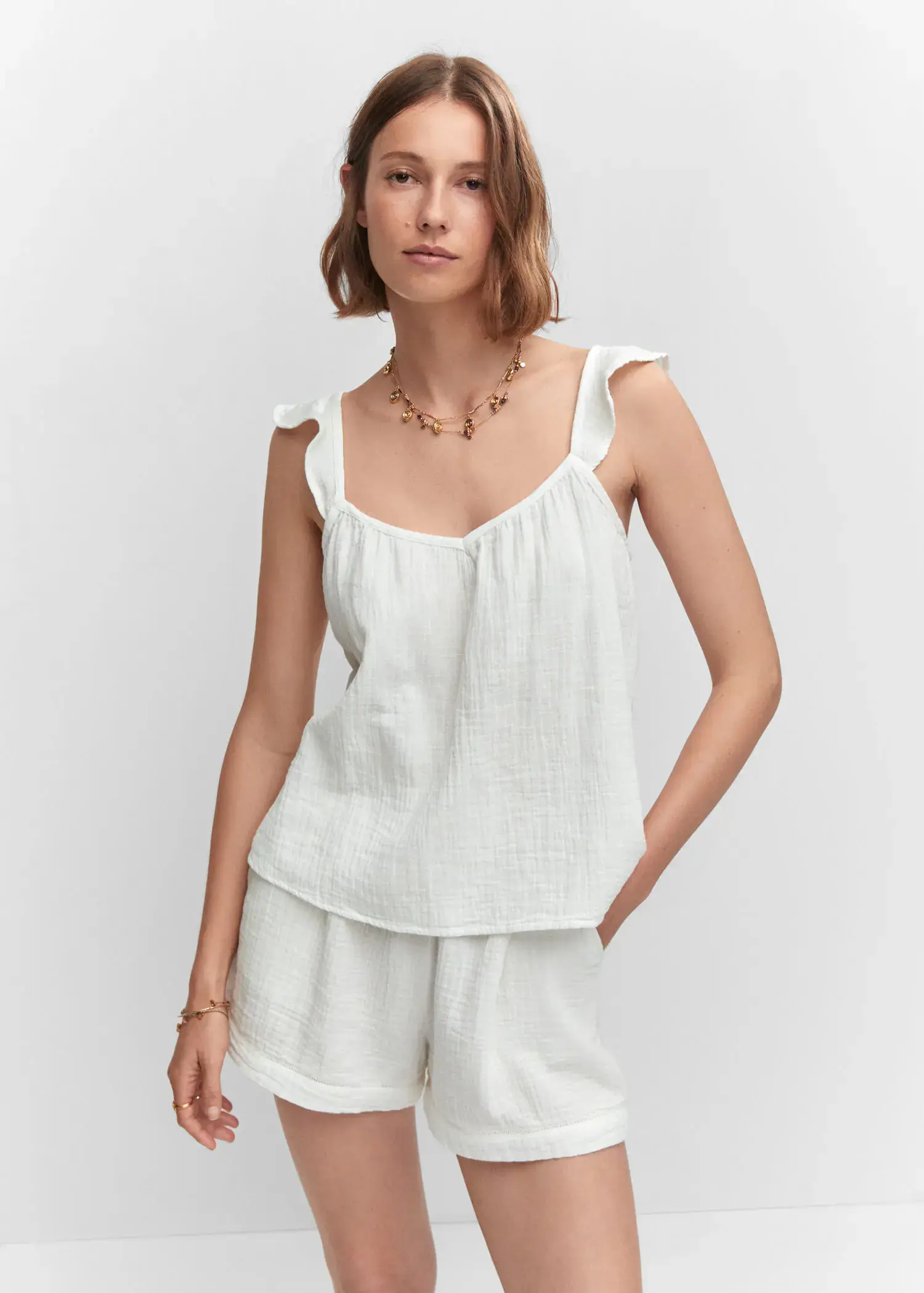 Mango Ruffled strap top. a woman wearing a white tank top and white shorts. 