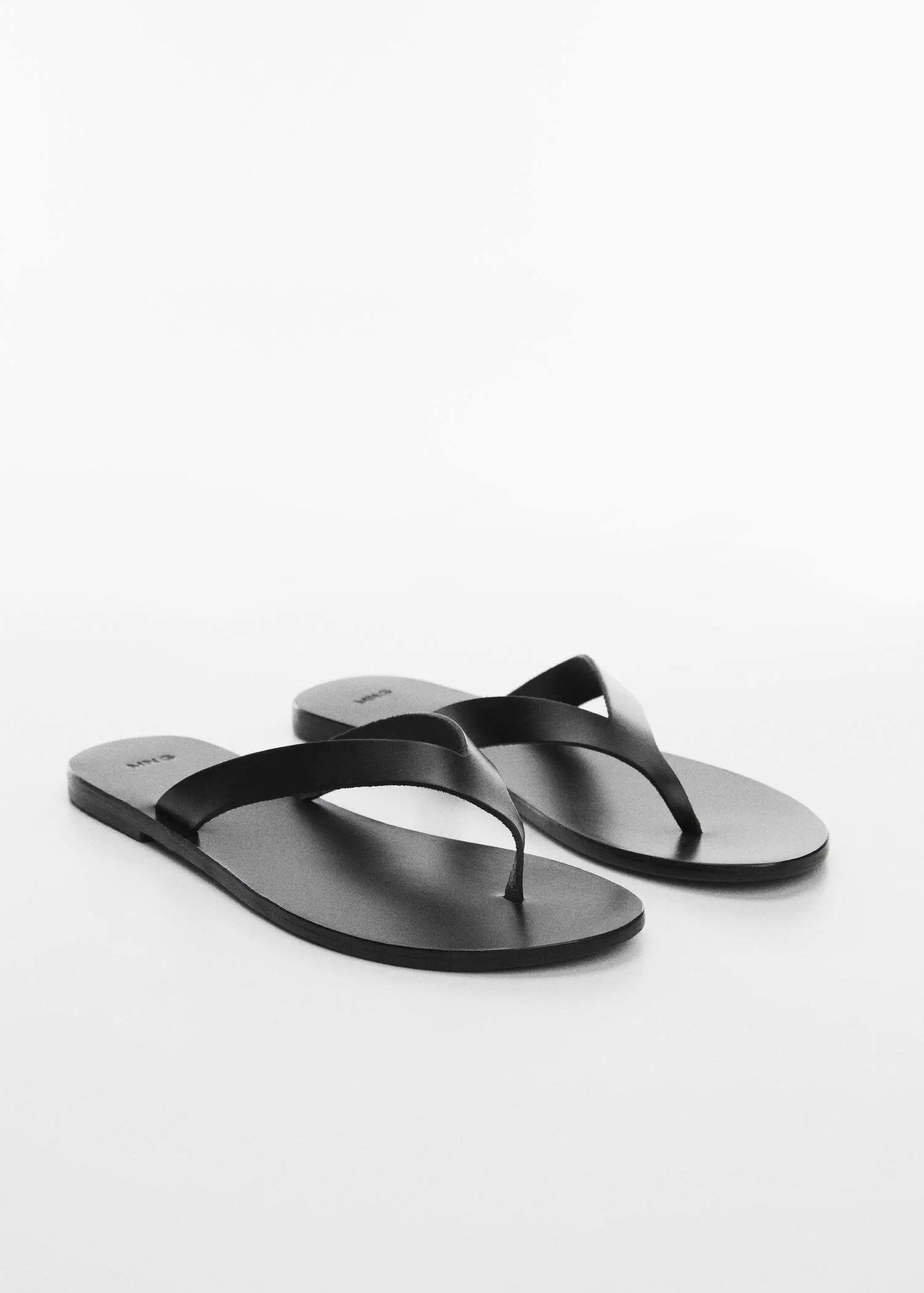 Mango Leather sandals with straps. a pair of black flip flops sitting on top of a table. 