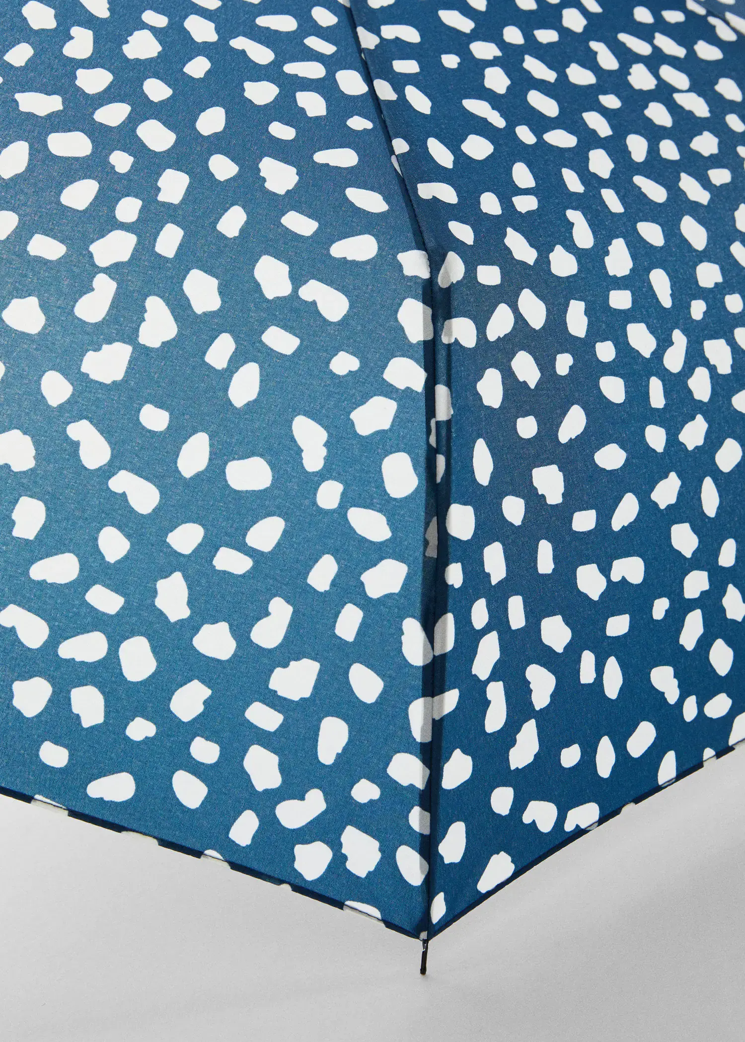 Mango Print folding umbrella. a close-up view of the corner of a bed. 