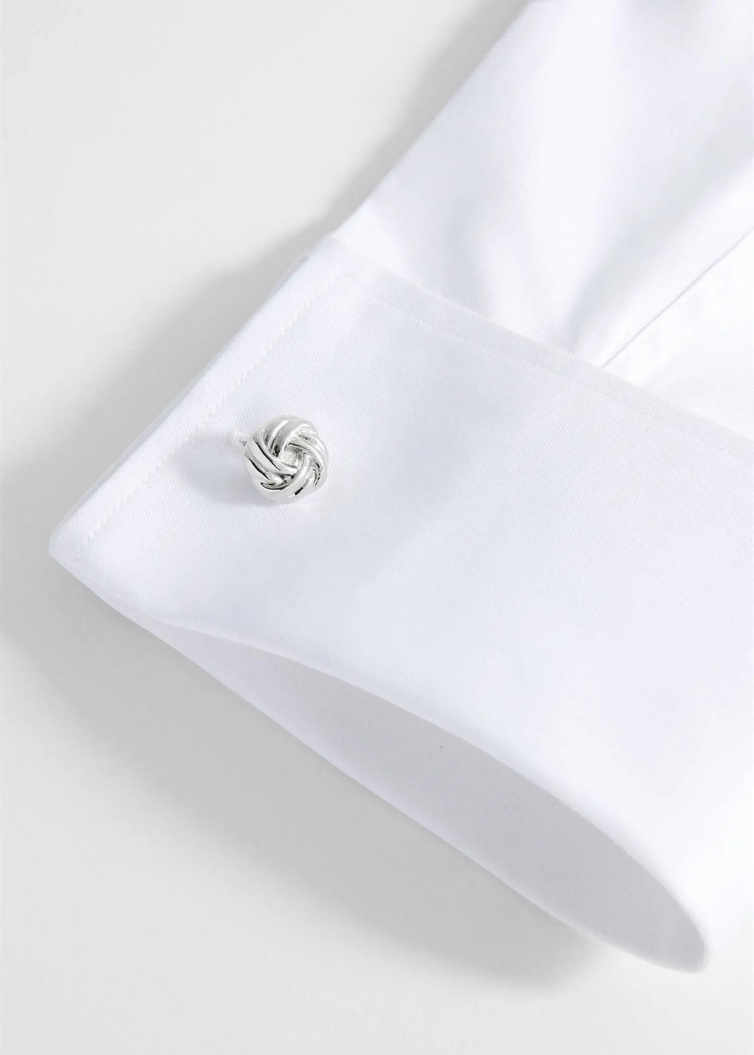 Mango 100% copper cufflinks with knot detail. a close-up of a white shirt with a knot on it. 