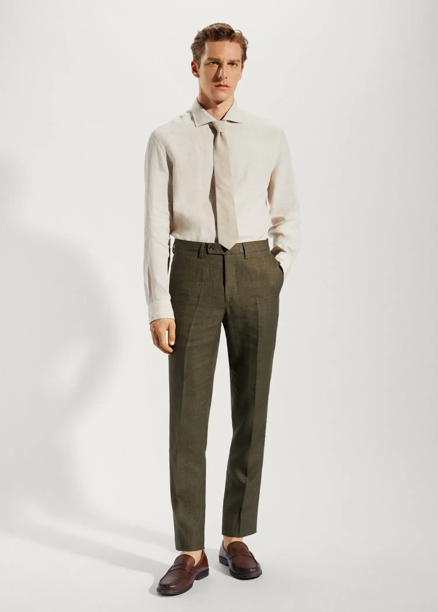 Mango 100% linen suit trousers. a man in a suit and tie standing in front of a white wall. 