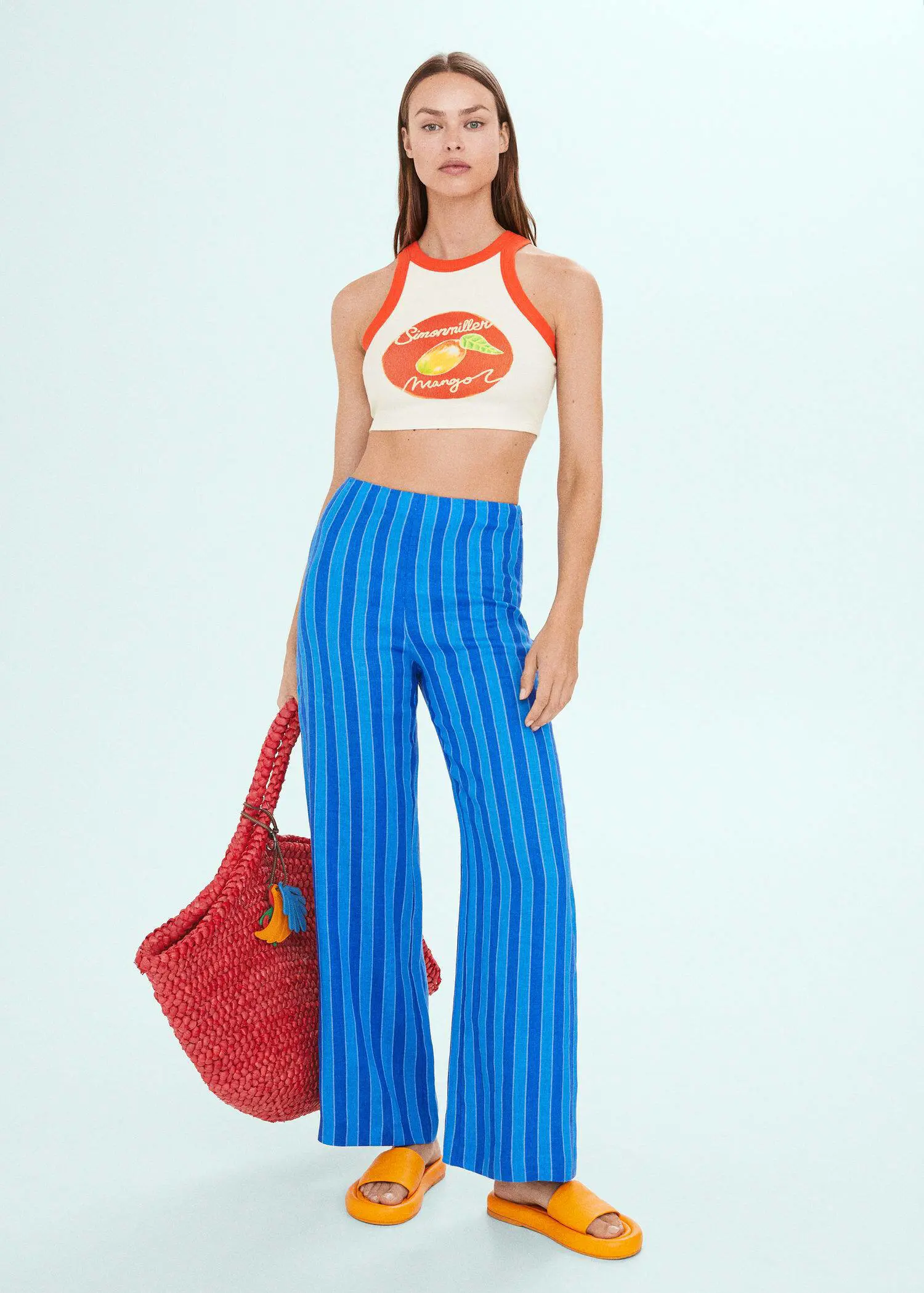 Mango Printed halter-neck cropped top. a woman in a white crop top holding a red bag. 