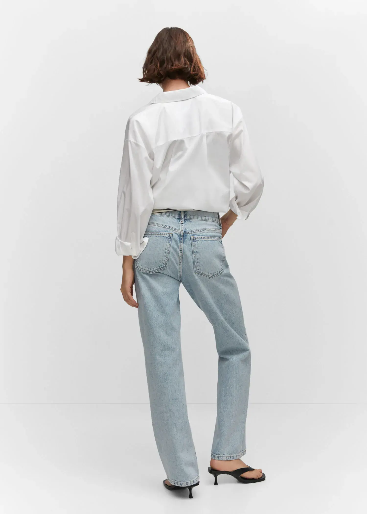 Mango Mid-rise straight jeans. a person standing in front of a white wall. 