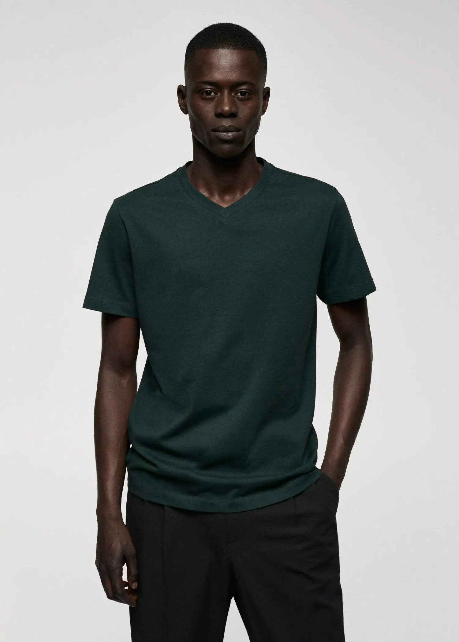 Mango Basic cotton V-neck T-shirt. a man wearing a dark green t-shirt and black pants. 