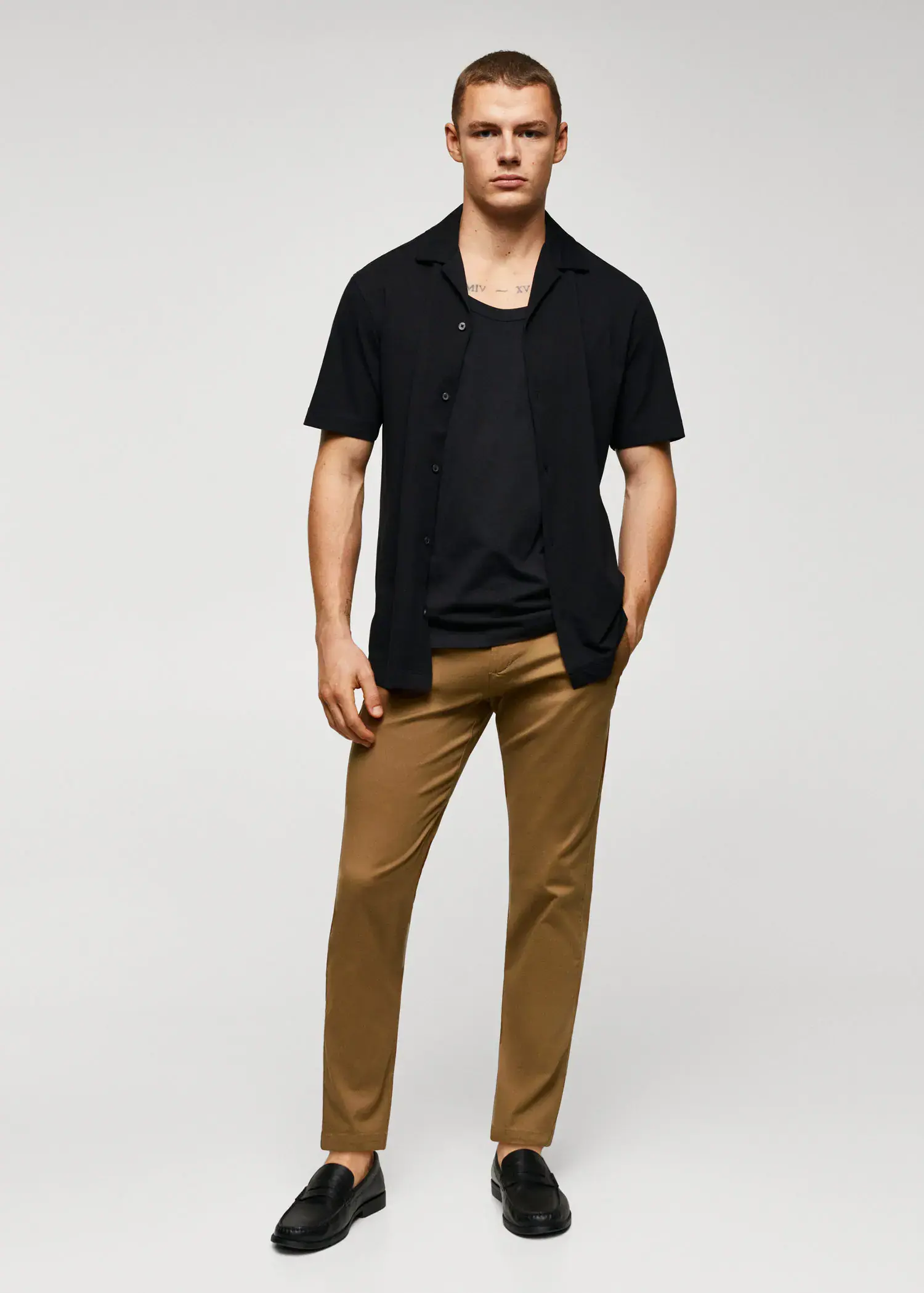 Mango Cotton tapered crop pants. a young man wearing a black shirt and brown pants. 