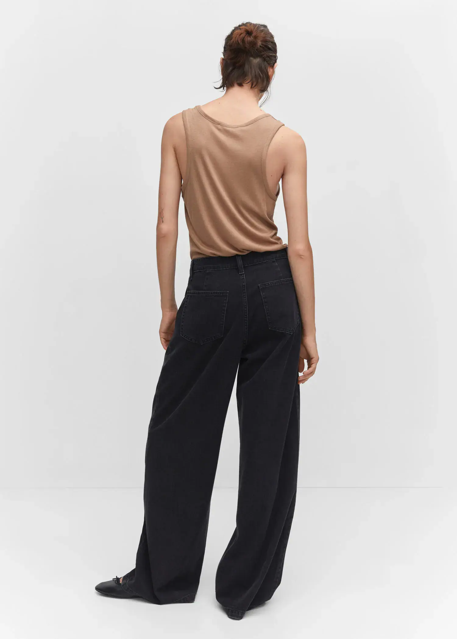 Mango Wide-leg pleated jeans. a woman wearing a tan tank top and black pants. 