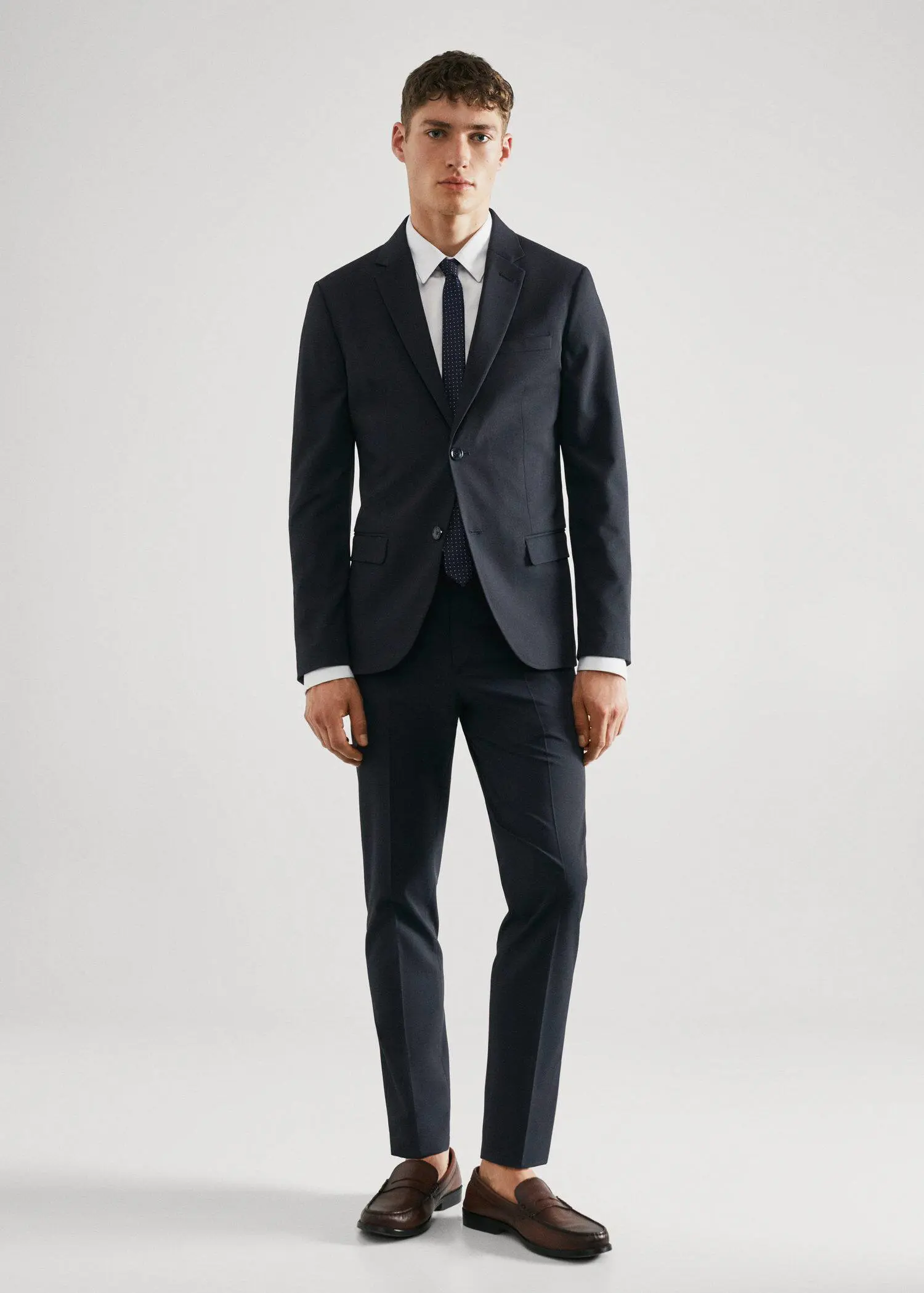 Mango Super slim-fit suit blazer in stretch fabric. a man wearing a suit and tie standing in a room. 