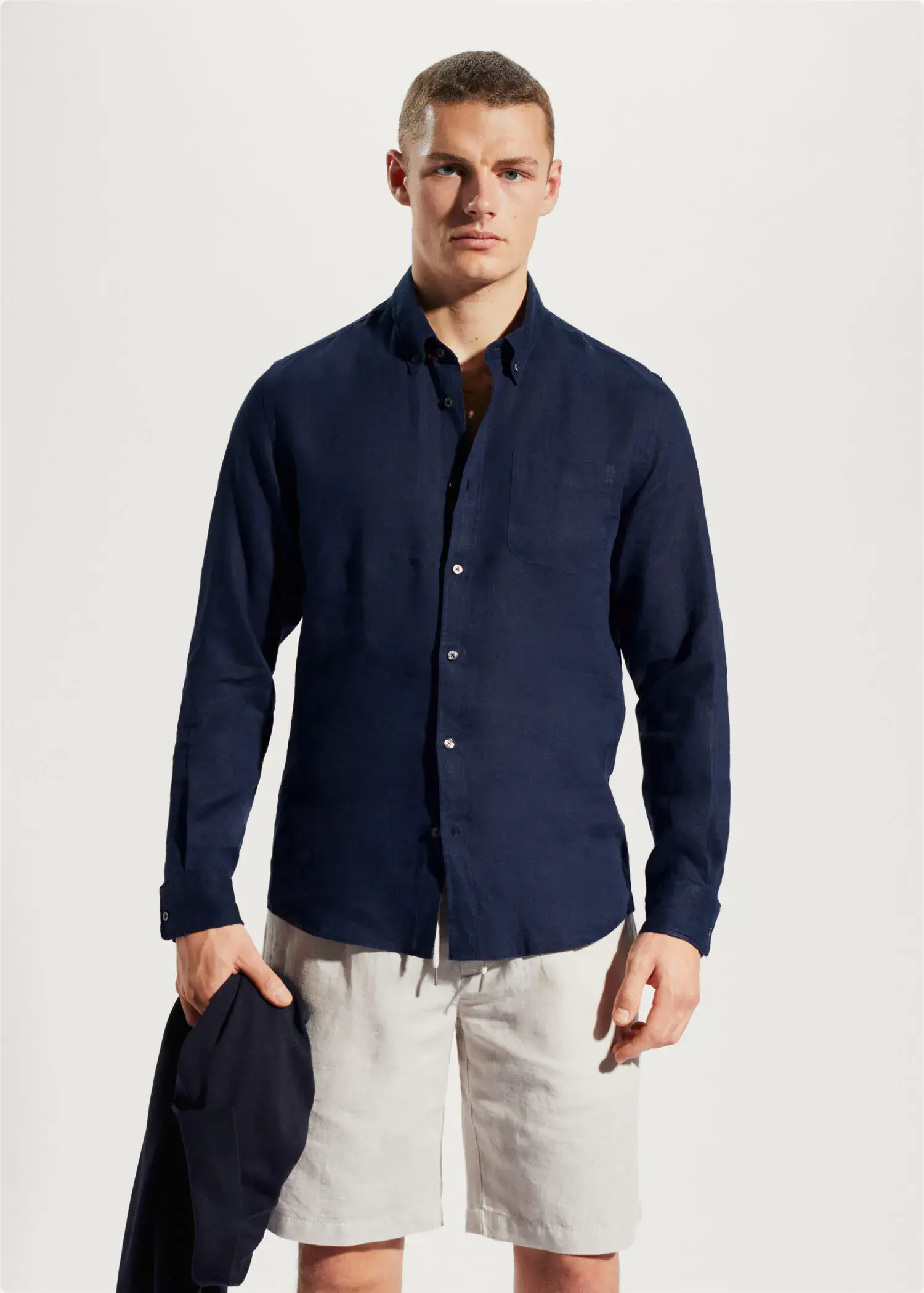 Mango 100% linen slim-fit shirt. a man in a blue shirt is holding a jacket. 