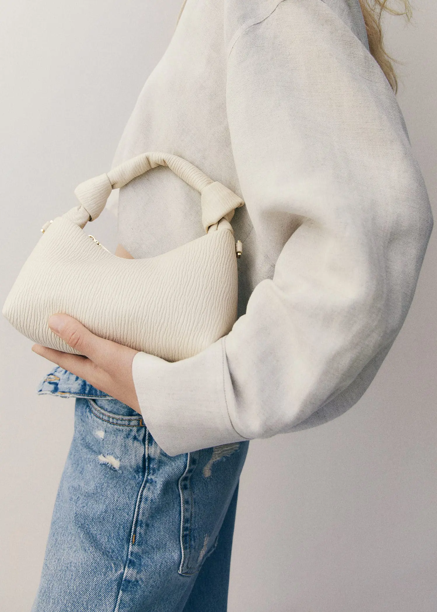 Mango Textured knot handle bag. a person holding a white purse in their hands. 
