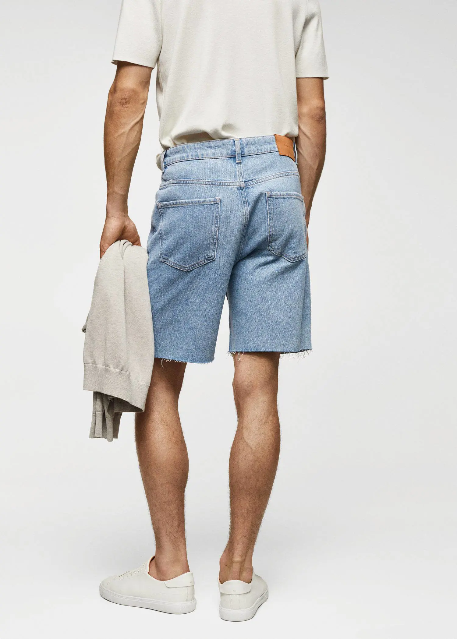Mango Regular-fit denim bermuda shorts. a man in blue denim shorts holding a jacket. 