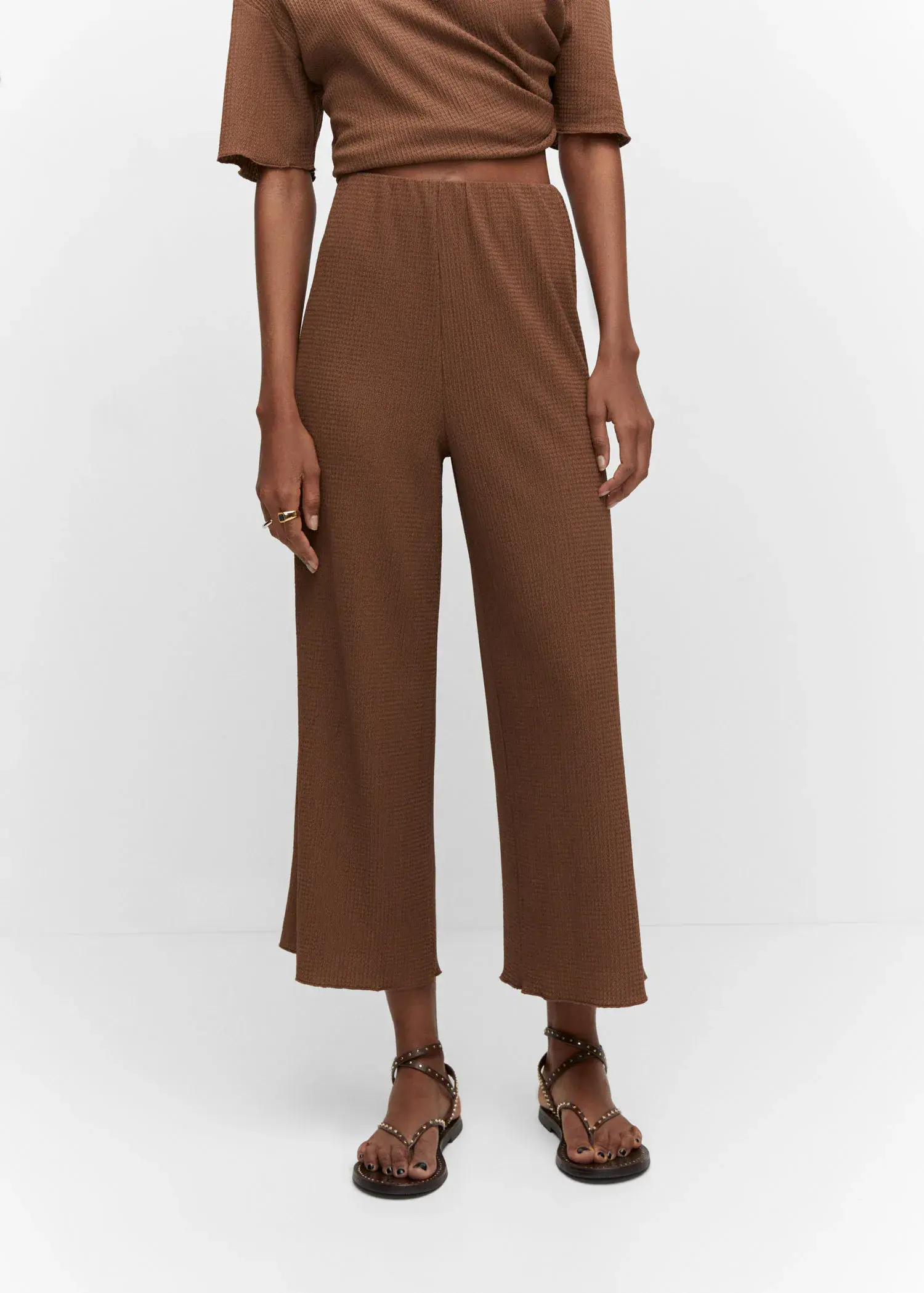 Mango Textured culotte trousers. a person standing in front of a white wall. 