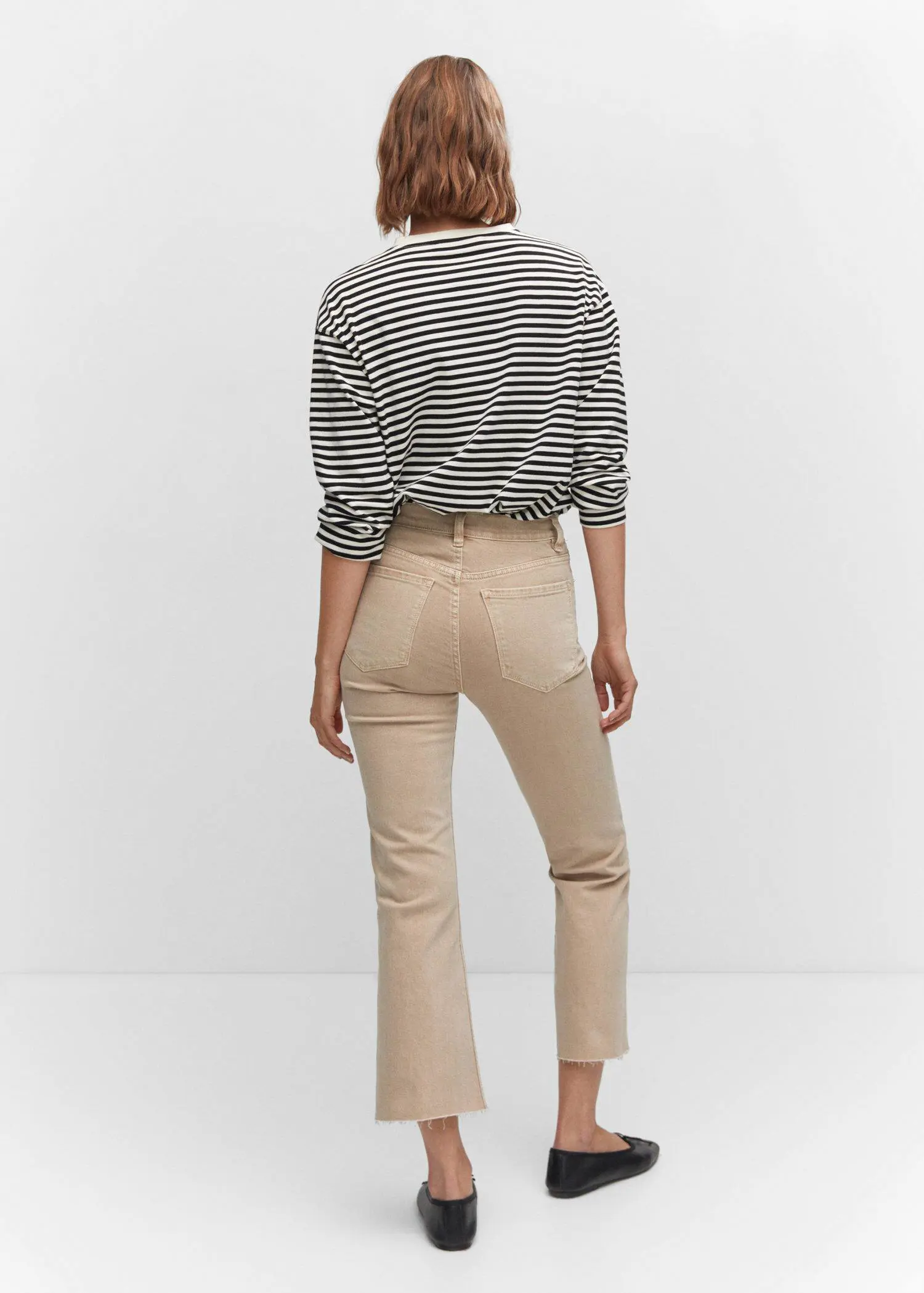 Mango Crop flared jeans. a woman wearing beige pants and a striped shirt. 