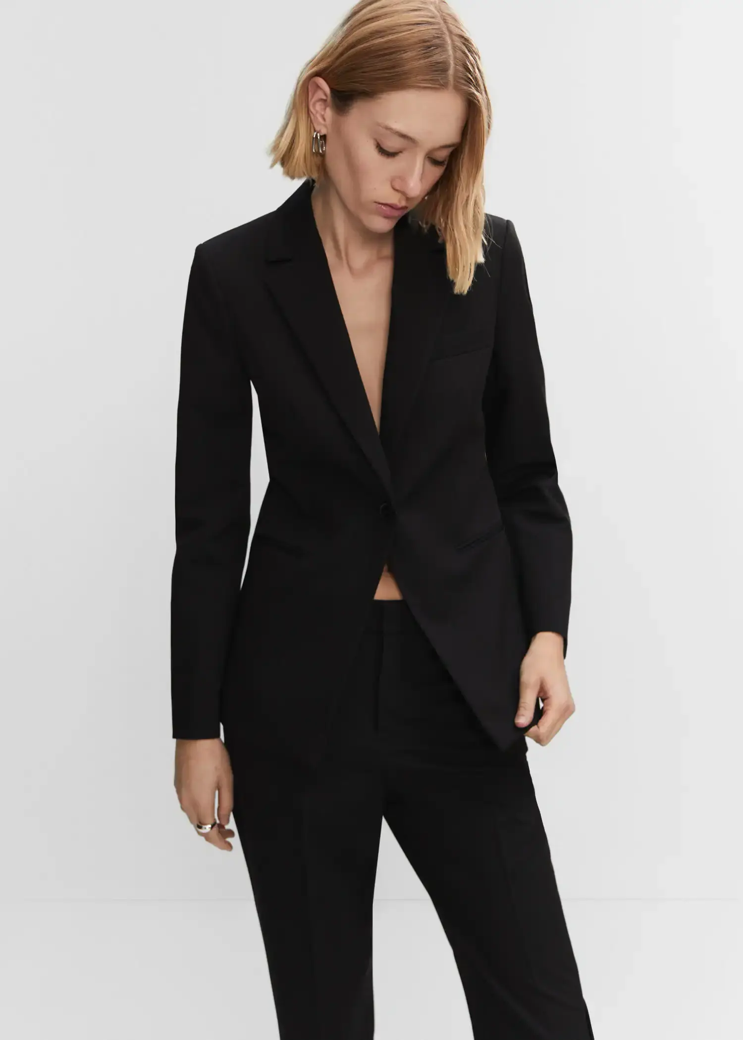 Mango Fitted suit jacket. a woman in a black suit is posing for a picture 